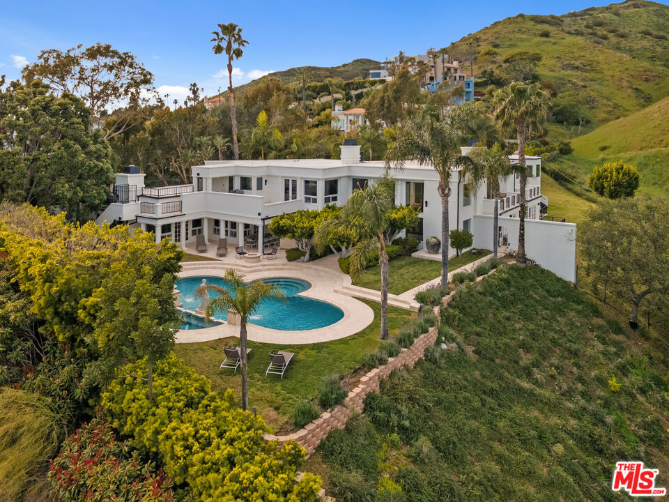 Take advantage of this opportunity to own a slice of the Malibu way of life. Relish in unparalleled poolside vibes with commanding views of the Pacific Ocean and infinitely spectacular sunrises in one of the most prestigious beachside communities around the world. This magnificent estate boasts sweeping views of white-water ocean, mountains and city lights that must be seen in-person. Delight in the sight of dolphin pods splashing through Latigo Bay, admire the lights of the Ferris wheel at Santa Monica Pier, and stargaze to the sound of crashing waves while watching planes take off and land at LAX. Effortlessly perched on a hillside as the capstone of a private cul-de-sac enclave and situated on approximately more than half an acre in the heart of Malibu just moments from Malibu Country Mart, the Malibu Pier, Soho House, Point Dume, acclaimed restaurants, and world-class beaches & hiking trails. Enter across a bridge spanning the open-air courtyard, which is gated for additional privacy. The modern multilevel floor plan features a sun-filled formal living room with double-height ceilings, picture windows and hardwood floors where glass doors lead to the ocean-view swimming pool and spa. The dining room, living room and newly remodeled gourmet chef's kitchen with Sub-Zero and Wolf appliances open onto a covered patio with built-in bbq and fire pit leading to flat grassy areas with ocean views. 5 ensuite bedrooms include a spectacular upstairs primary suite outfitted with dual walk-in closets, spa-style bath, sauna and private terrace overlooking the backyard and Pacific Ocean with glimmering views of the Queen's necklace, Downtown Los Angeles skyline and Santa Catalina Island. Amenities include a professional gym, wet-room with ocean and mountain views featuring a rain shower and soaking tub, office, wine cellar, 3-car garage, 8-camera video security system and Tesla charger. Enjoy Escondido Beach via PCH underpass along with nearby Solstice Canyon and Escondido Canyon Park with its hiking trails and seasonal waterfall. There is a waitlist available at Sycamore Park Beach and Tennis Club to purchase membership.