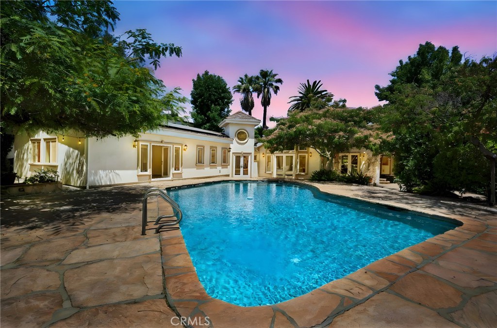 Welcome to this stunning single-story Tarzana home, south of Ventura Blvd, spanning 3,670 square feet with 5 bedrooms and 5 bathrooms, plus a versatile ADU at the rear. The converted garage now serves as a playroom, gym, or office, complete with a small kitchen and loft. Enjoy modern amenities like active security cameras throughout the entire home, solar panels for energy efficiency, and recessed lighting throughout. The expansive master suite features a fireplace, a massive walk-in closet, and a luxurious bathroom. Split central A/C systems ensure personalized comfort from two separate thermostats. The open-concept kitchen boasts granite countertops and stainless steel appliances, flowing seamlessly into large living areas perfect for entertaining. Outside, a nearly half-acre flat lot offers a sparkling pool, ample space for gatherings, and a paver circular driveway with dual automatic gates with additional parking on the side of the home. Gardener and pool service are included. *Some pictures have been virtually staged