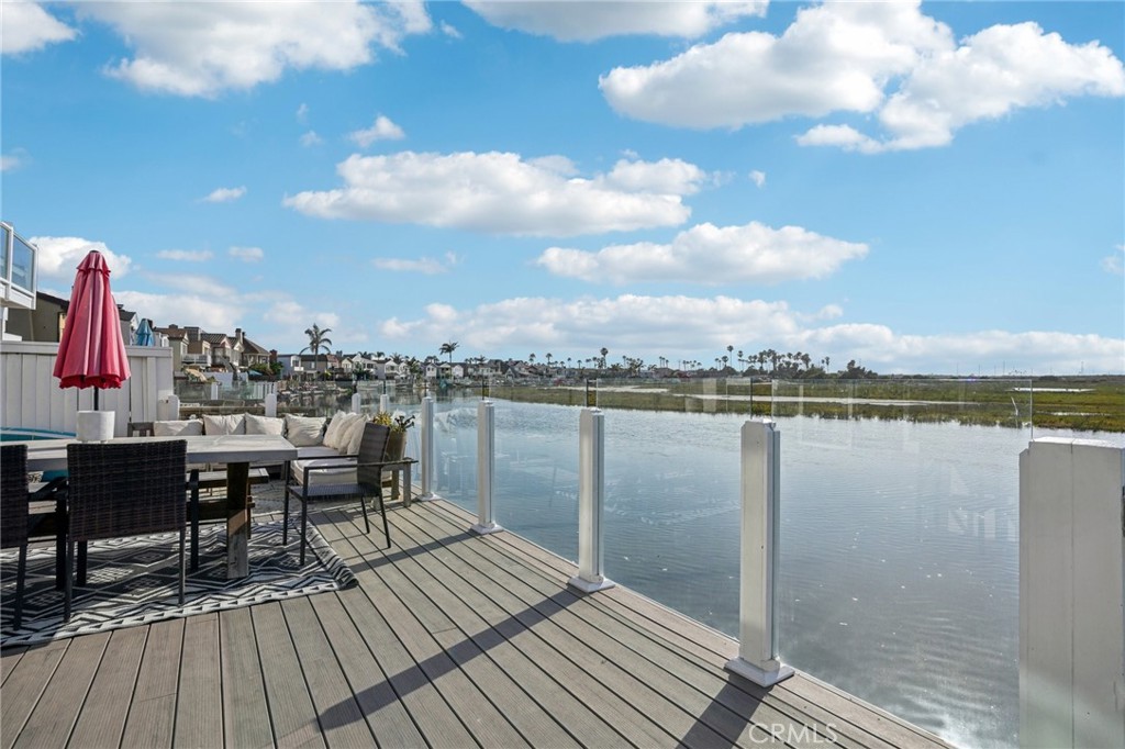 Enjoy ocean breezes and endless water views in this exceptionally remodeled four-bedroom, three-bath canal-front home. Featuring a stunning gourmet kitchen with quartz counters, top-of-the-line appliances, custom cabinetry, and an impressive island, this home is ideal for the inspired chef or entertainer. The open-concept living room and formal dining room offer hardwood flooring, custom lighting, a fireplace, and glass doors leading to a waterfront deck, ideal for taking in breathtaking water and sunset views. The primary suite includes a fireplace, a walk-in closet and a well-appointed ensuite bath featuring stone counters, custom dual-sink vanities, soaking tub, shower, and a water-view deck. The other three spacious bedrooms include recessed lighting and built-in closet systems. This home also offers an oversized two-car garage with extra space for surfboards, bikes, and general storage. Enjoy beach living and the amenities of the Newport Shores Community Association, including a pool, clubhouse, tennis, pickleball, basketball, volleyball, playground, and BBQ area.