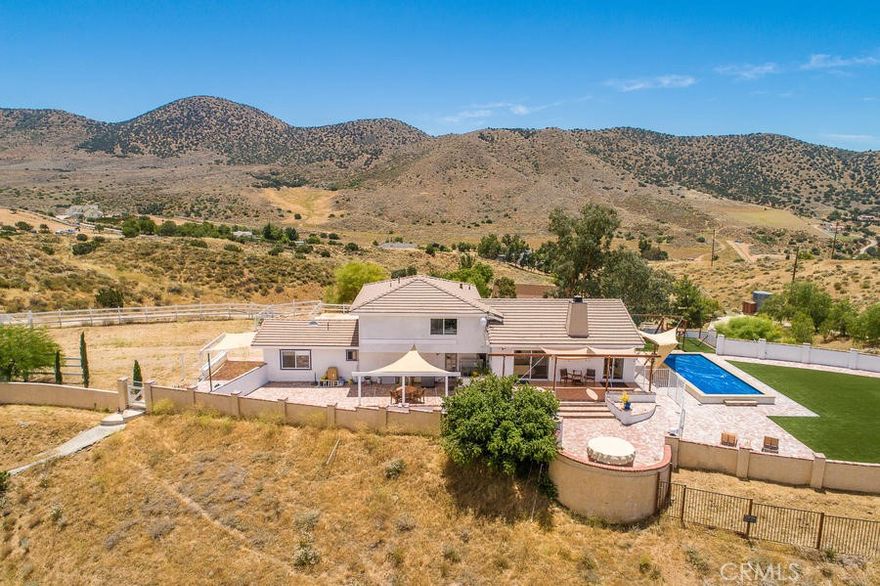 Panoramic, mountain paradise just 40 miles from LA in the charming, pastoral hamlet of Agua Dulce. A truly incredible work-from-home location. The hacienda sits on a hill with 300 degree views, just 10 minutes up the road from cinematic Vasquez Rocks. You will soak in a hot-tub overlooking two world-class horse training ranches, the Agua Dulce Winery, and historic Route 61, Sierra Highway. Enjoy a nearly new 12,000 ft3 salt-water, pebble bottom swimming pool, 3'6 deep with a 6'6 deep end. Watch pink sunsets over mountain silhouettes. The entire yard is ringed with brick flatwork and masonry walled (4ft) for privacy and peace of mind. Full of light, most windows are 4'x6'. Oak hardwood floors in the living/dining and upstairs, cool to the touch, earth-tone tile downstairs. Quartz countertops and like new appliances with large work/prep area behind oven. Interior is predominantly light grey paint. The living and dining rooms spill out onto a tiled deck. Oversized, top-of-the-line synthetic grass yard. In-wall 7+1 surround sound home theater. House can sleep 8 comfortably (1 queen poster bed, 2 queen wall-beds, 1 bunk bed, 1 twin with trundle, not including couches). Entire downstairs can be closed off as well as the downstairs workroom/guest bedroom which has its own bath, washing machine and bar area. Prior owners have kept 2 horses on the property, on in each of the 12x12' stalls. There is a shed for hay and ample paddock. 1 stall and hay area are available for storage as well as 40' container. CCTV security + Bing. 25x6mbs unlimited internet (Creative Wireless). DirectTV equipment is on property. The last half mile access to the property is a well groomed decomposed granite road. Amazon, trash and other delivery trucks come and go frequently. Plenty of parking, none covered. 95% efficient HIVAC, tankless water heater. Excellent service providers offer affordable, weekly pool service, trash pickup and landscaping. Well supplementation around $220/month. 500 gallons propane gas + 12kw generator on site.