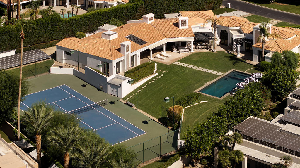 Tucked away behind the gates of Mission Ranch, one of Rancho Mirage's most coveted enclaves just off prestigious Clancy Lane, this single-level custom estate offers effortless elegance on nearly an acre of manicured grounds. The home is a study in relaxed sophistication, framed by lush green lawns, a resurfaced tennis court built to tournament standards, a newly redone pool and spa, and a mix of outdoor amenities including a fireplace, putting green, bocce court, and multiple covered patios--all designed for both lively entertaining and quiet retreat.The residence spans approximately 4,900 square feet and features four ensuite bedrooms, six baths, a media lounge, and a seamless indoor-outdoor flow. Vaulted and tray ceilings add a sense of volume, while wide-plank light oak floors bring warmth to the newly renovated interiors. A gracious entry leads to a formal living space anchored by a sleek wet bar, complete with Sub-Zero ice maker and wine storage--perfect for evening gatherings.The open-concept kitchen is a chef's dream, outfitted with top-of-the-line Viking appliances, Caesarstone countertops, a large center island, and a fully equipped butler's pantry. Nearly every room opens to the outdoors, embracing the desert light and surrounding mountain views.The primary suite is a private sanctuary, offering a cozy sitting room with fireplace, spa-style bath with freestanding tub, walk-in shower, sauna, and an oversized custom closet. Additional highlights include owned solar, full furnishings, and a rare sense of privacy throughout the property.Turnkey and timeless--this is desert living at its most refined.
