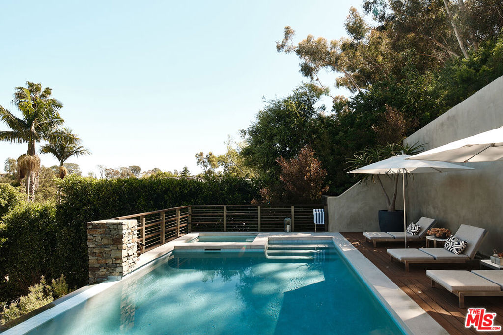 Nestled in the sought-after enclave of Rustic Canyon, this architectural gem was artfully crafted by acclaimed architect Michael Kovac. The home embodies completely custom, timeless design ensuring quality in every corner. Step inside to discover a formal yet relaxed living room effortlessly flowing to an additional open-concept living and dining space. Artistically framed floor-to-ceiling windows flood the rooms with natural light complimenting the warmth and richness of the hardwood accents while allowing the polished cement floors, and Boffi kitchen with Gaggenau appliances, to add a touch of modern sophistication. Ascend the exquisitely designed staircase to reveal a luxurious primary suite welcoming a sitting room, steam shower, office loft and private terrace. Envisioned for relaxation and entertaining, your outdoor oasis awaits featuring a marvelous infinity pool + spa, waterfall and picturesque treetop views. Four additional bedrooms, six bathrooms and a vast three-car garage complete the home. Don't miss this opportunity to call this Rustic Canyon gem home! * Home is 5,566 SF on public records