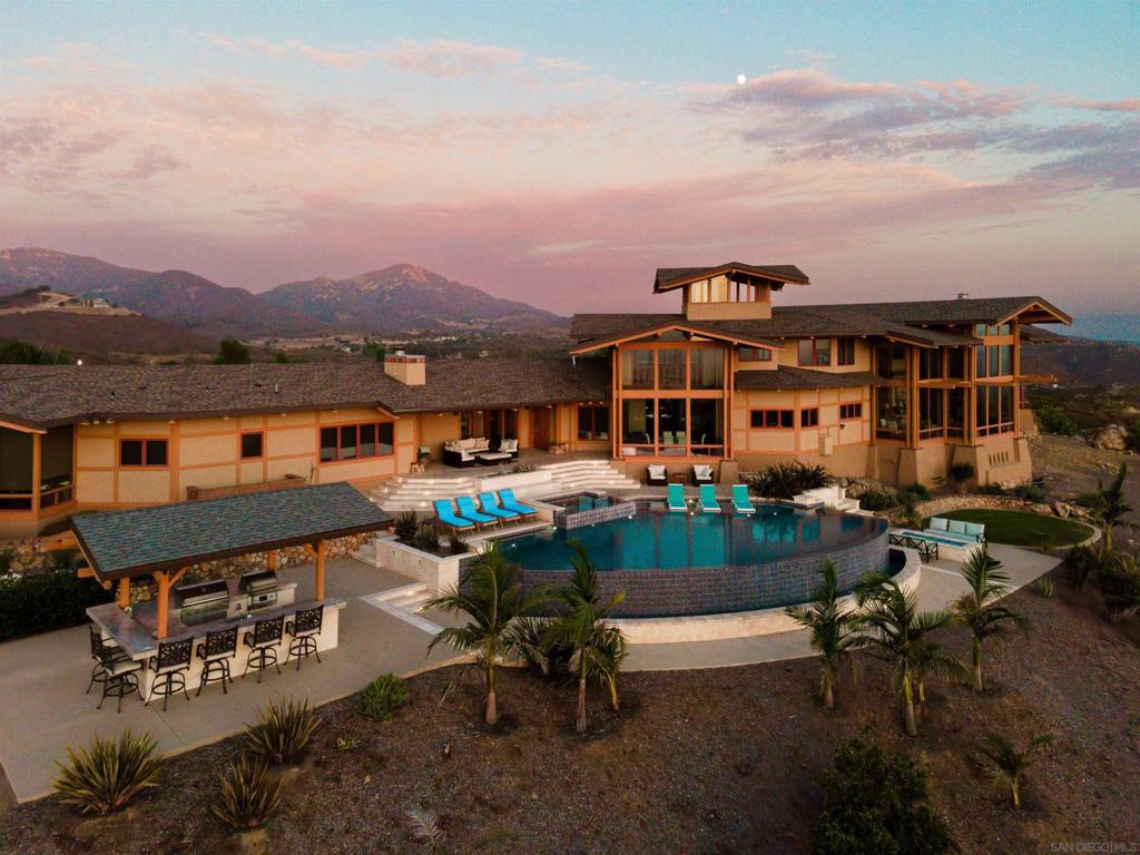 This exquisite luxury property, custom-designed by renowned architect Roger Mohling, offers an unparalleled living experience with ocean and sunset views from all rooms. Perched on a stunning landscape with panoramic views, the home exudes a lodge-like atmosphere, featuring exposed Douglas Fir Wood Beams, rich Brazilian Cherry Wood floors, and meticulously crafted stonework. The stained concrete floors blend seamlessly with the natural materials, enhancing the home’s earthy elegance. The chef’s dream kitchen is equipped with newer high-end appliances, complemented by quartz countertops, creating the perfect space for culinary excellence. The primary retreat offers a serene escape, complete with a cozy fireplace, his-and-her closets, and floor-to-ceiling windows that capture breathtaking views of city lights and panoramic sunset views. Enjoy new saltwater pool and spa by Majestic Pools. Included in this sale is an additional 42 ACRES for a total of 60 ACRES!!! The second parcel can be subdivided. The property is zoned for horses and agriculture, offering endless possibilities for those seeking a rural lifestyle. Fully functional garden, mature fruit trees and a chicken coop with nesting boxes, perfect for fresh eggs. The property also includes a spacious shed for storage, and 60 solar panels, providing sustainable energy to reduce electricity costs. Additionally, there is a second storage shed ideal for tools or equipment, and a charming koi pond as you enter the home. The gated and secured driveway ensures privacy and exclusivity, making this a true sanctuary! No HOA - This home has minimal utility bills, it is on septic, well and 60 SOLAR PANELS that are owned, with producing 19.2 KW hours. 42 ACRES adjacent to the east you can develop 3 homes with easements that is also included in the list price.