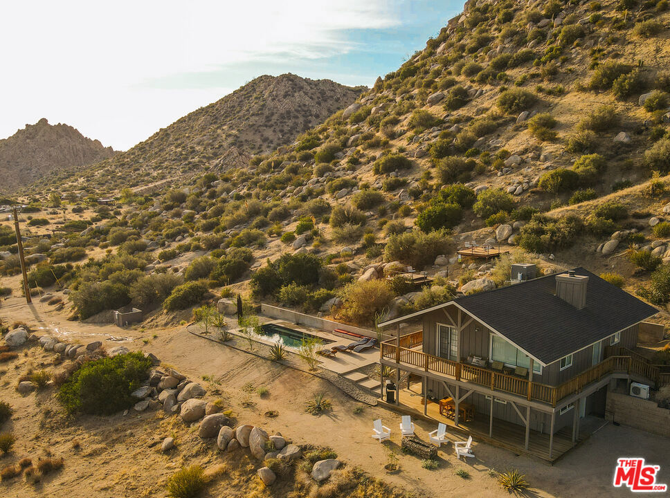 !!!MAJOR PRICE REDUCTION!!! A rare opportunity to own a licensed short-term rental, walking distance to the top Pioneertown attractions. Includes an easily transferrable short term vacation rental permit. - $125,000 in paid out and confirmed bookings (Jan 1- Dec 31 2025) with 60 open days remaining to book in 2025. Welcome to Pioneertown Vista! This rare, secluded property is the last house at the end of a quiet road, perched on the highest spot in town, yet just a short walk from iconic Pioneertown main strip. The property opens onto miles upon miles of untouched wilderness. Enormous boulders, breathtaking mountain and sunrise-to-sunset views and every imaginable luxury amenity, with no expense spared, make this an exceptional retreat. Some of the other property highlights include: a chef's kitchen with a large commercial gas range, outdoor shower, cathedral ceilings and city water.In the morning, step out of the nearly 500 sq. ft. primary suite, which occupies the entire main level, and head upstairs to greet the sunrise with a coffee on an oversized wraparound cedar balcony. Start your day with a hillside hike, a swim in the newly built heated saltwater pool, or a relaxing session in the built-in sauna. Unwind with a book while soaking in the spa overlooking the majestic valley, warm up by the fireplace in the golden sunset light, and listen to your favorite album on a vintage sound system. In the evening, stroll down to Mane St. for a craft cocktail at the Red Dog Saloon, knock down a few pins at Pioneer Bowl a time-capsule of mid-century modern space-age design or catch a show at Pappy & Harriet's, ranked among the top 20 music venues in the U.S. and host to legendary acts like Paul McCartney, Robert Plant, Lizzo, Patti Smith, and Lorde. Originally built as a movie set for Western films and TV shows, Pioneertown is now experiencing a renaissance a second coming that even Roy Rogers and Gene Autry couldn't have imagined when they designed the town in the 1940s. Just a short drive away are the amenities of Yucca Valley, the stunning landscapes of Joshua Tree National Park, and, a few miles farther, the museums, galleries, restaurants, and world-class airport of Palm Springs. This property is currently operating as a profitable, highly rated, year-round vacation rental with a 5.0-star review history and can be delivered with a management team, furniture and original artwork. Possible adjacent (front of property) lot available under another listing agent.
