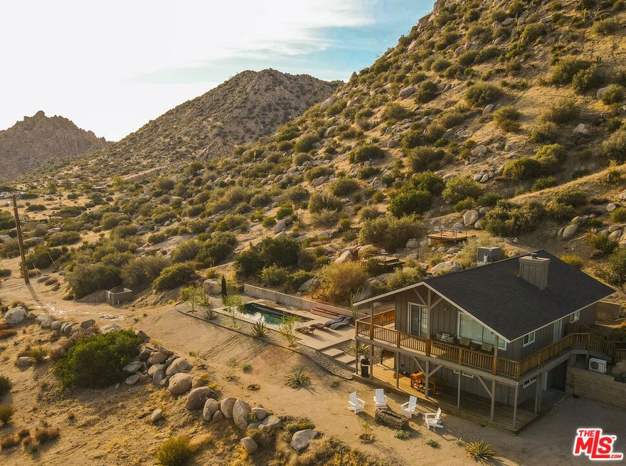 !!!MAJOR PRICE REDUCTION!!!                          A rare opportunity to own a licensed short-term rental, walking distance to the top Pioneertown attractions.  Includes an easily transferrable short term vacation rental permit. - $125,000 in paid out and confirmed bookings (Jan 1- Dec 31 2025) with 60 open days remaining to book in 2025.   Welcome to Pioneertown Vista!   This rare, secluded property is the last house at the end of a quiet road, perched on the highest spot in town, yet just a short walk from iconic Pioneertown main strip.  The property opens onto miles upon miles of untouched wilderness. Enormous boulders, breathtaking mountain and sunrise-to-sunset views and every imaginable luxury amenity, with no expense spared, make this an exceptional retreat. Some of the other property highlights include: a chef's kitchen with a large commercial gas range, outdoor shower, cathedral ceilings and city water.In the morning, step out of the nearly 500 sq. ft. primary suite, which occupies the entire main level, and head upstairs to greet the sunrise with a coffee on an oversized wraparound cedar balcony. Start your day with a hillside hike, a swim in the newly built heated saltwater pool, or a relaxing session in the built-in sauna. Unwind with a book while soaking in the spa overlooking the majestic valley, warm up by the fireplace in the golden sunset light, and listen to your favorite album on a vintage sound system. In the evening, stroll down to Mane St. for a craft cocktail at the Red Dog Saloon, knock down a few pins at Pioneer Bowl a time-capsule of mid-century modern space-age design or catch a show at Pappy & Harriet's, ranked among the top 20 music venues in the U.S. and host to legendary acts like Paul McCartney, Robert Plant, Lizzo, Patti Smith, and Lorde.   Originally built as a movie set for Western films and TV shows, Pioneertown is now experiencing a renaissance a second coming that even Roy Rogers and Gene Autry couldn't have imagined when they designed the town in the 1940s. Just a short drive away are the amenities of Yucca Valley, the stunning landscapes of Joshua Tree National Park, and, a few miles farther, the museums, galleries, restaurants, and world-class airport of Palm Springs. This property is currently operating as a profitable, highly rated, year-round vacation rental with a 5.0-star review history and can be delivered with a management team, furniture and original artwork.   Possible adjacent (front of property) lot available under another listing agent.