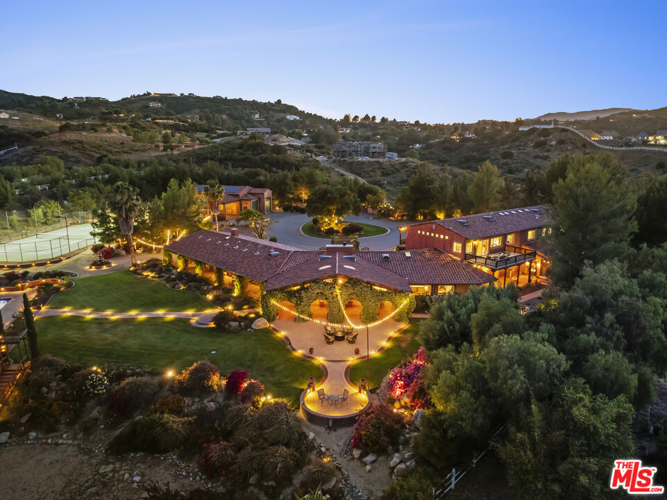 Welcome to your private paradise. Discover an extraordinary lifestyle in this breathtaking gated estate, nestled on over 5 pristine acres in the prestigious La Cresta community. Tucked away at the end of a private cul-de-sac, this expansive Hacienda-style main residence offers over 7,500 square feet of luxurious living space, seamlessly blending serenity, elegance, and panoramic views of the valley, mountains, and sparkling city lights. Step inside to find a gourmet, remodeled chef's kitchen outfitted with top-of-the-line stainless steel appliances, heated floors, and a charming dining nook. The main level showcases a secluded, opulent primary suite complete with a private office, large walk-in closet, and a spa-inspired bathroom, beautifully renovated for ultimate relaxation. The warm and inviting living room features a custom fireplace and vanishing doors that open effortlessly onto an expansive patiocreating the perfect setting for indoor-outdoor living and entertaining. Upstairs, you'll find five additional bedrooms and an oversized entertainment/media room with a private balcony, offering stunning views of the estate and surrounding landscape. The resort-style grounds are truly awe-inspiring. The outdoor spaces include a sparkling pool, a professional-grade tennis court, a built-in BBQ area, sauna, and ample green spaceyour own personal oasis where every day feels like a vacation. Guests will be delighted by the private casita, complete with a bedroom and kitchenette, as well as a separate 1,150 sq. ft. guest house featuring two bedrooms, full kitchen, living room, and a private backyard. Fully owned solar panel system (64 panels, 20.16 kW). Car enthusiasts and hobbyists alike will appreciate the expansive motor court, oversized garage/workshop with three 14-foot roll-up doors ideal for RVs, motorhomes, and more and an additional four-car garage with generous storage and parking options. Fully fenced and cross-fenced with a secure gated entrance, this exceptional property offers unparalleled privacy, space, and the finest in Southern California lifestyle living. A rare and remarkable offering come experience the magic of this one-of-a-kind La Cresta estate.
