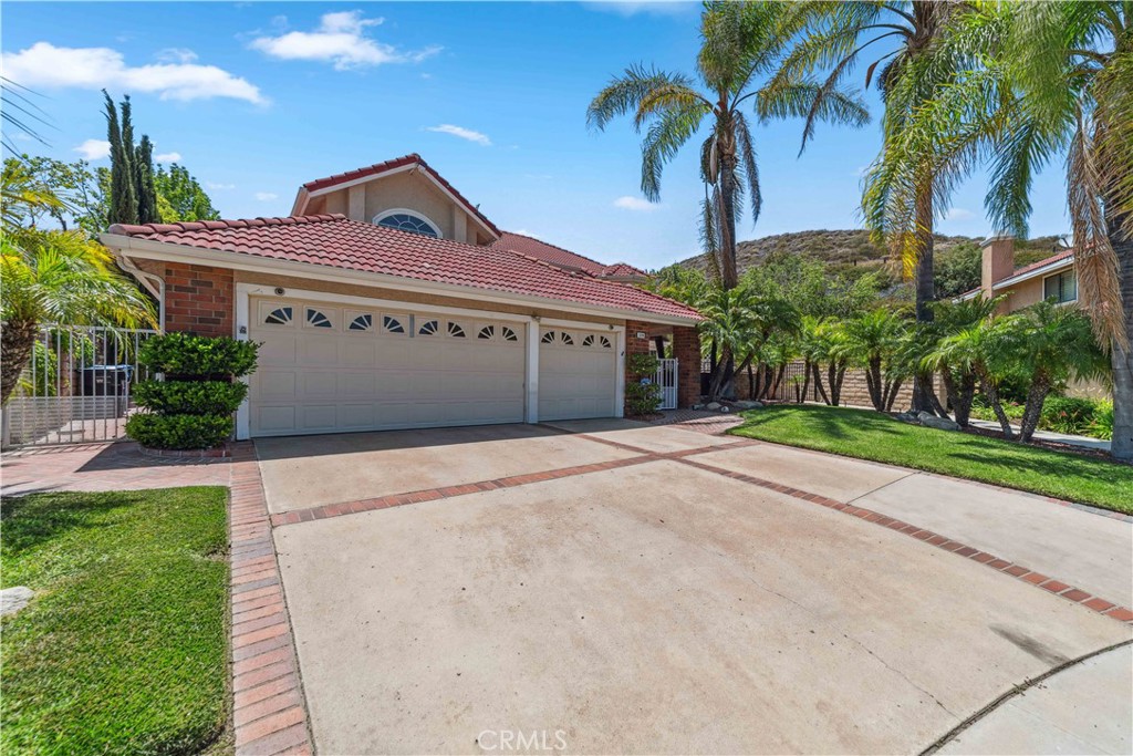Tucked at the end of a quiet cul-de-sac in sought-after Indian Hills Estates, this beautifully updated two-story home offers over 3,000 sq ft of living space on a sprawling ¼+ acre lot with southwest-facing views of treetops and the Simi Hills Golf Course. A charming brick courtyard entry framed by palm trees leads to double leaded-glass doors, opening into a grand two-story foyer and elegant living room with picture windows and a marble fireplace. Designed for both comfort and entertaining, this 4-bedroom, 3-bath home includes a 3-car garage and a resort-style backyard featuring a sparkling fenced pool, elevated spa, and a grassy green yard dotted with roses, tangerine, lemon and avocado trees. The gourmet kitchen boasts granite countertops, a large center island with ZLINE 6-burner stove, tumbled tile backsplash, and rich wood cabinetry. A cozy bay window frames the breakfast nook, while the formal dining room comfortably seats ten. Multiple living spaces—including the dining, living, and spacious family/media room with fireplace—open to covered brick patios and serene views. The downstairs bedroom is perfect for guests or a home office. Upstairs, the luxurious primary suite features vaulted ceilings, fireplace, mountain vistas, a private Saltillo-tiled balcony, and a spa-like bath with soaking tub, separate shower, dual sinks, and generous counter space. Two additional bedrooms—one with a bay window and one with its own patio—complete the upper level. Recently painted, newly carpeted, plus a fire safe tile roof, its move-in-perfect. Enjoy this home the way you choose, there is no HOA or associated dues to pay. Just minutes from Chumash Park, Simi Hills Golf Course, trails, schools, shopping, dining, and the 118 freeway. This is the Simi Valley lifestyle at its best.