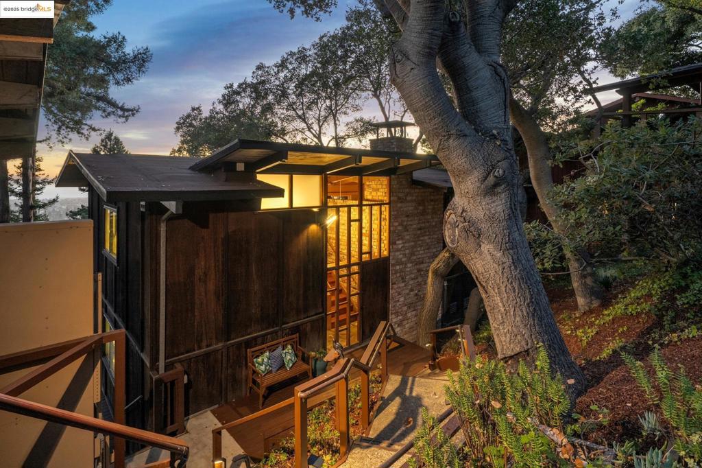 This 1963 Mid-Century Modern home was designed by Bob "Red" Kleyn-Schorel, a cousin of Bernard Maybeck's daughter-in-law. The design throughout pays homage to Maybeck's brilliance, featuring high ceilings, wood exteriors, Craftsman elements, and a perfect siting on a verdant hill, creating a beautiful intersection of nature. Upon arrival, you notice the beautiful wood detailing of the grand front door, expansive front porch, and the symmetrical roofline. The home captures Maybeck's belief that "hillside architecture is landscape gardening around a few rooms in case of rain." This home boasts green, beguiling vistas from nearly every room. You feel enveloped by nature, as it captures the very essence of Maybeck's intent: beauty. The bedrooms are large and inviting. Built-in bookshelves, a grand fireplace, and the enormous open space make the home feel truly extraordinary. Upgraded bathrooms retain a connection to the outdoors, evoking a spa-like ambiance. There is ample storage, and the garden runs all the way to the street below. The view of the campus, bay, and flickering lights creates a calm, peaceful ambiance. The quiet cul-de-sac has no through traffic. 5 Maybeck Twin Drive, a street named playfully after Maybeck's twin granddaughters, is a once-in-a-lifetime opportunity.