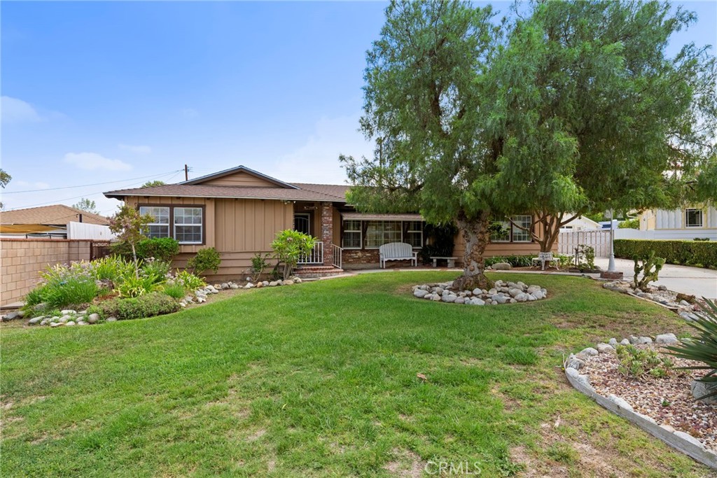 Welcome to this expansive residence in the heart of West Covina, offering a perfect blend of classic character and tasteful updates. Enter inside and discover original hardwood floors that flow throughout the entire home, highlighted by a charming brick gas fireplace and a wall of windows that fill the living room with natural light. The formal dining room features elegant French doors that open directly to the backyard, creating an ideal setting for gatherings. The large kitchen is a chef’s delight with warm oak cabinetry, dark granite countertops, and dual ovens, providing both function and style. A bonus den offers additional living space with a second brick fireplace, a dry bar, and sliding doors leading out to the backyard oasis. The main bathroom is tastefully updated with dual sinks and modern countertops, while the primary suite boasts a private en suite with a glass-enclosed shower and updated flooring. Both additional bedrooms feature built-in storage, and a convenient indoor laundry room comes equipped with extra cabinets. Outside, you can enjoy a covered patio, a sparkling in-ground pool, and a grassy lawn. A rear picket-gated area makes the perfect dog run, while the long driveway and detached 3-car garage offer ample parking and storage. Located behind the garage is a pool changing room ideal for guests as well as a separate rumpus room perfect for use as a hobby room, game room, home gym or office! Set on a massive lot, this home offers incredible space inside and out—perfect for entertaining, relaxing, and creating memories.