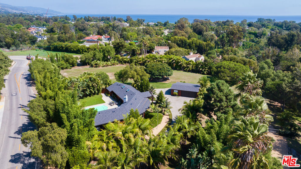 This beautifully appointed Point Dume retreat has been exquisitely updated and remodeled to create a tropical paradise! The sale includes ~1.8 verdant acres, one of the flattest and most usable lots in the area, with deeded Riviera II beach rights to Little Dume. Behind the gate lies a long driveway lined with palms, completely enclosed by fencing, mature trees, and privacy hedges. Inside, the main home offers an open-concept floor plan and high ceilings that create beautiful natural light along with recessed lighting and rich, vintage wood beams. The living room centers around a stone fireplace and features a full bar with seating and a private outdoor patio. A Chef's kitchen offers marble countertops, Viking appliances, and a large island with a wraparound breakfast bar and second sink. The primary suite is a peaceful sanctuary with sliding glass doors leading to the lush backyard, a separate enclosed patio, and a spa-like bathroom featuring a water closet, soaking tub, dual vanities, and a walk-in closet. An adjacent room offers an ideal office, den, or nursery. The comfortable guest bedroom has a vaulted wood ceiling, two closets, and an en-suite bathroom. There is an additional powder room connected to the backyard. Outside, enjoy a verdant oasis with a large pool and a massive sun-filled patio enclosed by mature trees, perfectly suited to both entertain and recharge. A detached garage offers two covered spaces, plentiful storage, and a separate gym. There is a 1 bed/1 bath guest house with a separate driveway and enclosed grounds, complete with a well-equipped kitchen, living room, and private deck with an outdoor shower and bathtub. The coveted beach rights to Little Dume provide private access to the prized sandy beach, blocked from the prevailing west wind and perfectly situated to capture south swells. This trophy property is ready to be enjoyed, expanded upon, or further developed to suit any need. Property must be sold concurrently with the adjacent vacant lot at 6517 Zumirez Drive, also listed for sale.