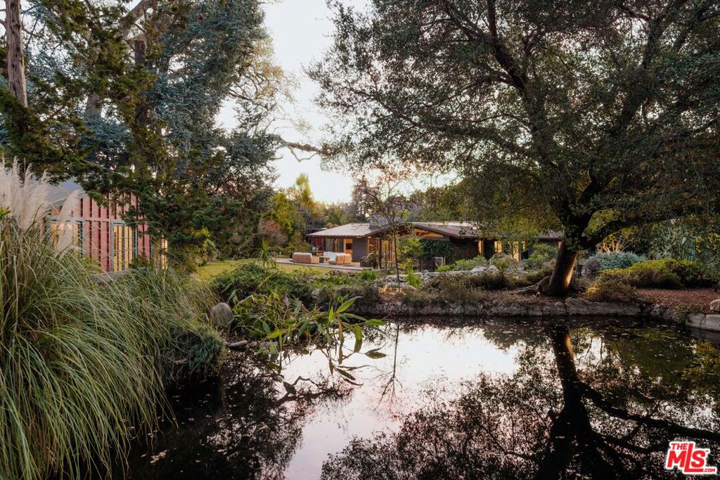 A rare offering in the heart of Encino, this exceptional estate at 17407 Rancho St and 4750 Encino Ave spans nearly 2.5 acres, seamlessly blending historic charm with modern luxury. This dual-property compound features two main residences, two guest houses, and three additional residences, including a restored mid-century home with a state-of-the-art recording studio, a writer's cottage, and a barn guest house. Designed for both grand entertaining and private retreats, the estate is rich in amenities. The picturesque barn with a bunkhouse, horse corrals, and turn-out creates an equestrian haven, while the spa, sauna-retreat, and aerie offer relaxation amidst lush, natural surroundings. The property also includes a library, pub, butler's kitchen, maid's quarters, and workshop, catering to a lifestyle of comfort and convenience. The park-like grounds feature serene koi ponds, meandering pathways, and a resort-style pool framed by mature trees, offering a private oasis in the city. A once-in-a-lifetime opportunity to own a truly versatile and inspiring compound, perfect for artists, creatives, and those seeking an unparalleled living experience.