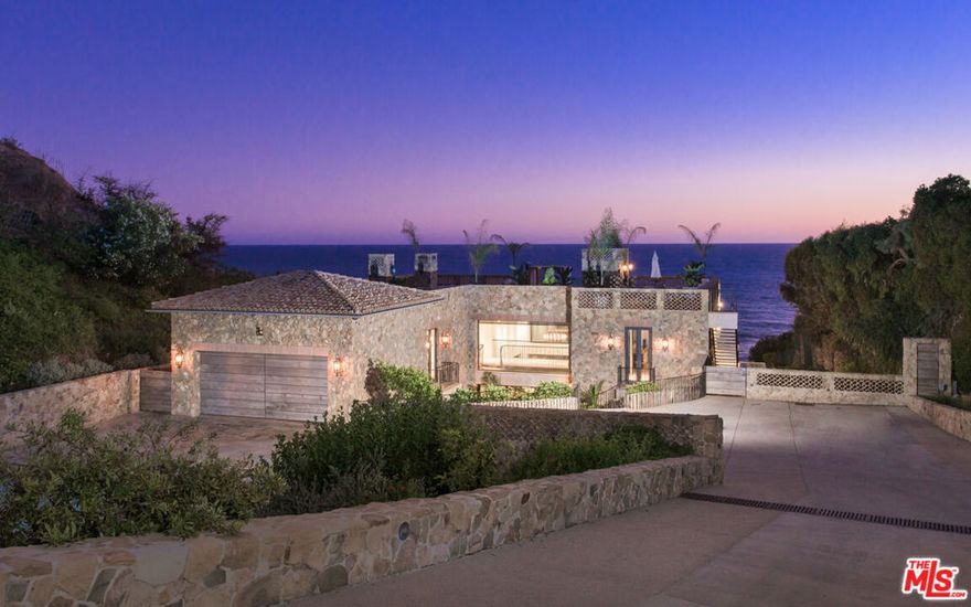 Casa di Pietra is a stunning beachfront villa with a gentle sloping terraced path to the beach combines bold lines and spacious interiors with exceptional quality to create a true architectural masterpiece. Exceedingly private and beautifully landscaped, the Doug Burdge-designed home sits at the end of a long gated drive, where it commands sensational ocean, shoreline, and island views. Seamless indoor-outdoor spaces invite lavish entertaining and luxurious living on one of Malibu's most sought-after beaches. The estate's distinctive rough-hewn stone exterior opens to reveal a magnificent, spacious interior of rare quality and understated details that maximize the views, light, and a feeling of tranquility. At the heart of the main floor is a huge great room that features a living area with double-height ceiling and fireplace, a dining area, and an ultra-sleek restaurant-style kitchen with breakfast bar, and home theater. A wall of windows disappears to bring the outdoors in and extend the home's entertainment area. Adjoining the living room area is a den/entertainment/game room. Two en-suite bedrooms complete the main floor.At the top of the curved floating stairway, a bridge separates two gracious ocean-view master suites, each with a fireplace, private deck overlooking the pool, and a spa-inspired bath. There is also an additional bedroom on this level. An expansive and very private rooftop terrace with fireplace and fire pit sitting areas is perfect for casual dining, sunset cocktails, and stargazing. The resort-style backyard takes in the full panorama of sea and sky, with swimming pool and spa, two convenient outdoor showers, outdoor kitchen with barbecue and pizza oven, dining and sitting area, and grassy lawns. With a large motor court, ample guest parking, and an immaculate collector's garage.