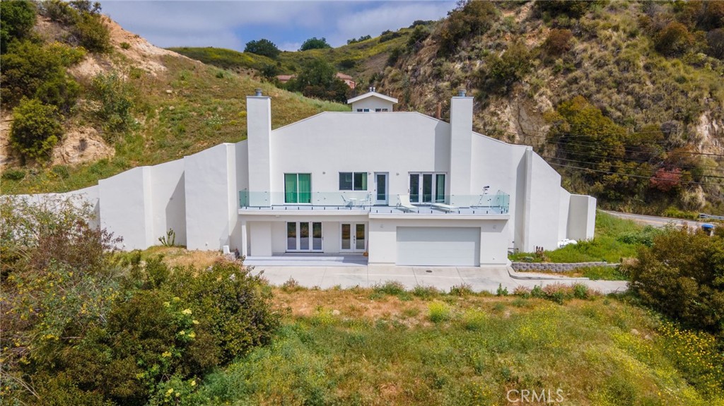HOME BUILT INTO HILLSIDE! This home isn’t just unique—it’s unforgettable. Expertly built into the hillside, this architecturally distinct dome home blends modern design with the natural landscape, offering a level of privacy, protection, and character you won’t find anywhere else in Los Angeles County.
Tucked into the mountain itself, the structure was designed with both beauty and strength in mind—engineered to stand strong against earthquakes, fires, and floods. All while showcasing stunning, panoramic views of the surrounding canyons and hills.
The master suite is a peaceful retreat, complete with a fireplace, private balcony, and a large walk-in closet—plus two more closets for added space. The spa-inspired bathroom features a deep soaking tub, a separate steam-ready shower, and sleek, high-end finishes.
Upstairs, two additional bedrooms offer their own incredible views. The chef’s kitchen is built for both form and function, with a central island, three sinks, a dual-source oven with pot filler, and a walk-in pantry for serious storage.
A dedicated theater or family room with its own bathroom provides the perfect space to relax or entertain.
This is more than just a home—it’s a one-of-a-kind living experience that combines smart design, natural serenity, and modern luxury. A rare opportunity to own something truly special.
Please note: All interior photos have been virtually staged for inspiration purposes only—no structural or original elements of the home have been altered in any way.