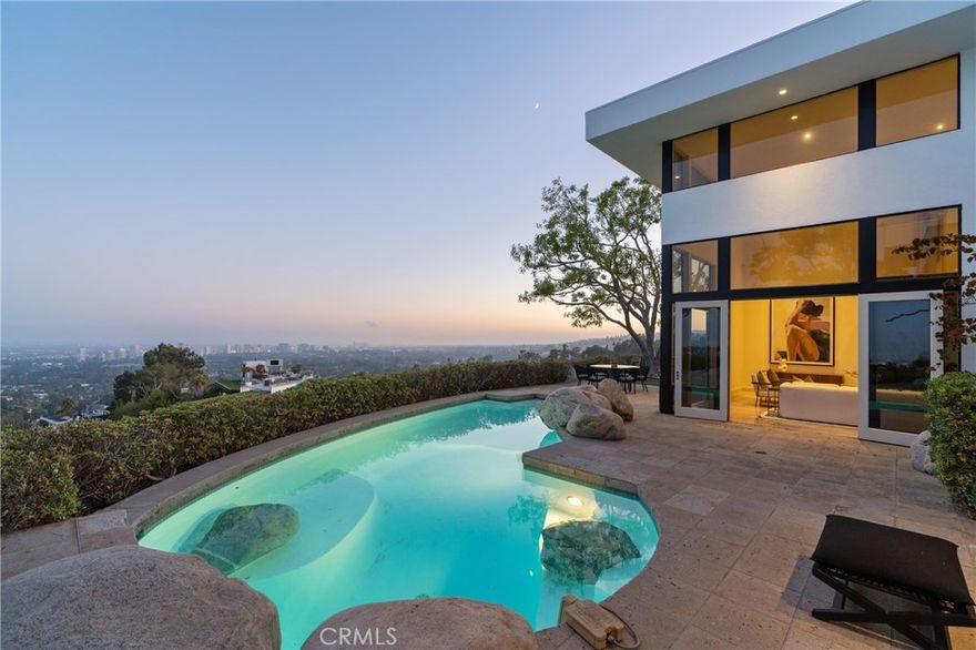 Tucked behind gates at the end of a long private driveway, this extraordinary contemporary estate sits on nearly an acre of prime promontory land, offering absolute privacy and some of the most commanding, unobstructed views in all of Los Angeles. From downtown to the ocean, every sunrise and sunset becomes a daily masterpiece. Walls of glass and picturesque windows frame panoramic vistas from nearly every room. Inside, the residence features 4 spacious bedrooms, a library, dedicated office, and a voluminous living room with soaring ceilings. A versatile bonus room is ideal as a gym, playroom, 5th bedroom, or den, while wellness amenities include a sauna and an indoor sports court with a professional basketball hoop. Designed for seamless indoor-outdoor living, French doors open to a resort-style pool area perfect for entertaining or quiet reflection. A generous garage with direct access and a large motor court provide ample parking. A rare opportunity to live in a one-of-a-kind Beverly Hills sanctuary where world-class privacy meets breathtaking natural beauty.