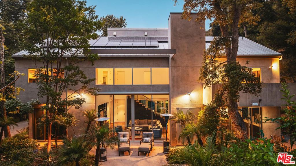 This private compound, designed by an architect for himself and his family, spans over 2.5 acres of lush, wooded grounds in the coveted lower Riviera, tucked away for ultimate seclusion down a 600 foot long driveway. A contemporary masterpiece, the residence feels like a work of art, showcasing refined design elements such as skylights, angular lines, walls of glass, and a sophisticated, loft-like ambiance. Built around mature oak and sycamore trees, a major element of the design is the connection between the living spaces and the outdoors. The main living area offers generous seating and seamless views of the surrounding greenery, anchored by 10 feet tall by 17 feet wide glass doors that "disappear" to connect the room with the outdoors as well as a striking, exposed glass staircase. The chef's kitchen is outfitted with Miele and Monogram appliances, an island and a large counter with seating that opens into the dining room and living area, making it ideal for both entertaining and everyday living. Upstairs, the primary suite is a sanctuary immersed in treetop views, complete with a spa-like bathroom featuring Statuary marble, custom cabinetry, and a soaking tub. Additional bedrooms and bathrooms are equally refined with high-end finishes throughout. Over the detached garage, nestled in the tree tops, is a self-contained studio apartment with its own kitchen and full bathroom offering a flexible space perfect for guests, a home office, a peaceful meditation retreat, or ADU. Outdoors, enjoy a built-in kitchen with BBQ and wood-burning pizza oven, expansive patio spaces, and meandering gardens that offer a true sense of escape amidst nature. Mainhouse is 4,000 sqft. ADU is 900 sqft. Total sqft = 4,900 per the seller.