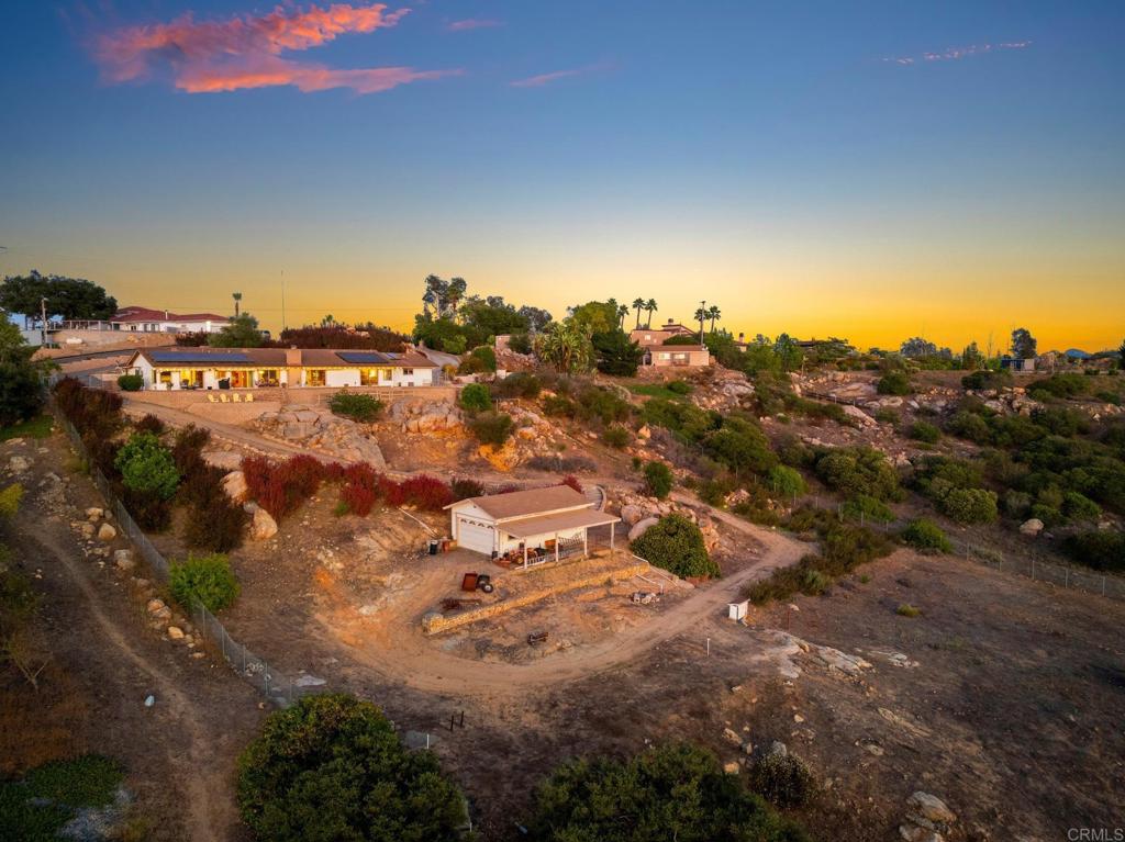 Single-Story Custom Retreat with Panoramic Views, Paid Off Solar, and Endless Possibilities! Welcome to 13065 Via Suena, an exceptional single-level custom home on 2.51 acres in the desirable “Via Suena Country Estates” in West Valley Center. Designed for comfort, sustainability, and effortless living, this meticulously maintained 3-bedroom, 2.5-bath home offers 2,335 sq. ft. of open, light-filled space with no interior steps and a layout that maximizes privacy and views from multiple rooms and locations. Built with solid 2x6 construction, and designed to take full advantage of its elevated west-facing orientation, the family room, living room, kitchen, and primary suite all enjoy sweeping panoramic views and spectacular sunsets. Relax in the tranquil front courtyard, dine on the rear patio, or follow the stone steps to a peaceful lower sitting area—this home invites indoor-outdoor living at its best. Say goodbye to high energy bills! Enjoy significant savings and sustainability while mitigating power outages with an owned photovoltaic solar system with 34 power producing panels and a Tesla Powerwall covering nearly all current energy usage. This all-electric home also features a solar water heater, QuietCool whole-house fans, a cozy wood-burning stove, and a living room fireplace with “heatilator”, keeping you comfortable year-round while reducing costs. The primary suite includes a walk-in closet, ceiling fan, and luxurious remodeled bathroom with quartz counters, soft-close cabinetry, dual shower heads, radiant heat, and brushed nickel finishes. The kitchen offers sunset views, a large center island, direct patio access, pull-out storage, and a pocket door to the dining room. Outside, a versatile 20’x30’ detached outbuilding with a roll-up door, water, interior lighting, and a 30-amp subpanel offers endless options—workshop, storage, studio, future ADU. The usable lot includes a fully fenced back yard, mature citrus trees, options for RV parking, vineyard, pool, or ADU, and two separate driveways for convenient access, parking for multiple vehicles and gorgeous rock walls made of local stones. Located just minutes from I-15, shopping, dining, and golf, this private oasis blends rural tranquility with modern convenience—with no HOA. This is more than a home—it’s a lifestyle. Don’t miss your chance to own a piece of Valley Center paradise. Schedule your private showing today!