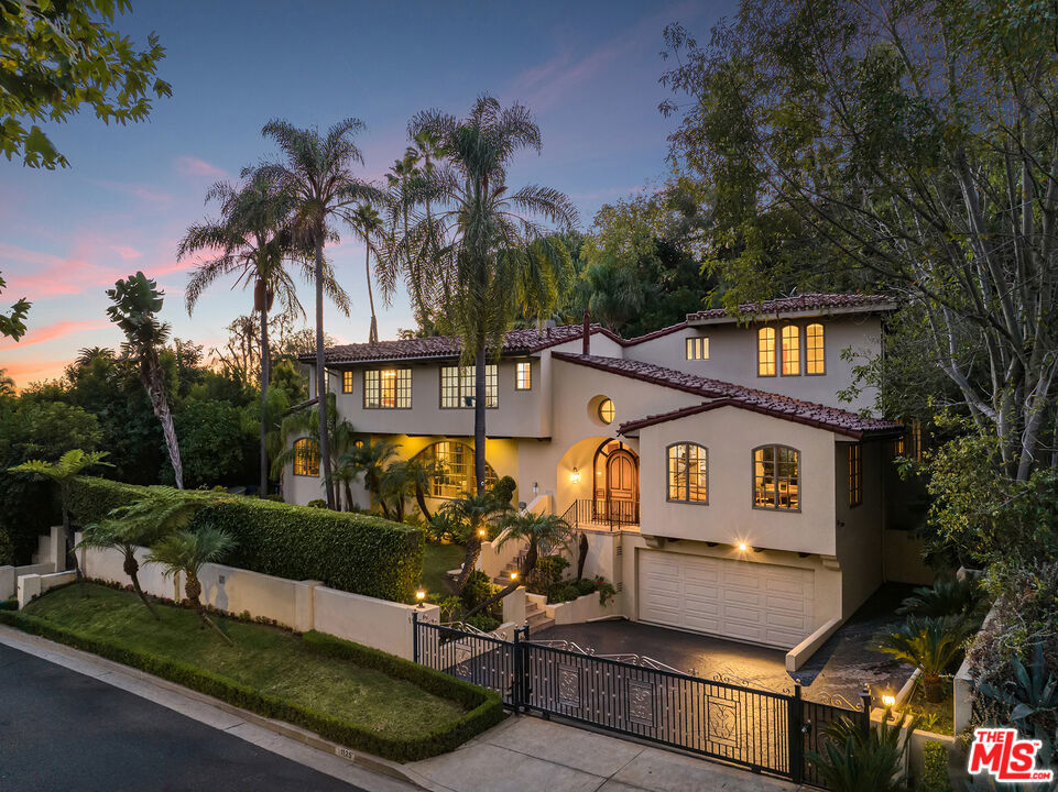 Positioned on prime lower San Ysidro Drive, north of Sunset Boulevard, this masterfully crafted Mediterranean estate spans approx 5,665 SF square feet on a sprawling 12,426 square foot lot, embodying elegance and luxurious seclusion within the heart of Beverly Hills. Hedged and gated, the residence is framed by mature landscaping, towering palms, and fruit trees, creating a serene compound. Upon entry through custom-carved doors, the residence unfolds with architectural precision arched windows, beamed ceilings, and warm wood floors exude refined character. The main level offers a grand living room with a well-appointed wet bar, fireplace and adjoining office, a formal dining room for elegant gatherings, and an open chef's kitchen with a central island and stainless appliances. This inviting space flows seamlessly into the family room, complete with a cozy fireplace, creating a floor plan that balances intimacy with functionality. The upper level reveals an expansive primary suite with a pitched ceiling, sitting area, fireplace, and a private terrace overlooking the backyard. The ensuite bath is a spa-like sanctuary with dual vanities, a steam shower, a soaking tub, and an extensive walk-in dressing room. Three additional large ensuite bedrooms are thoughtfully designed with fine finishes and custom details. On the lower level, find a staff room with a full bath, a laundry room, and an oversized bonus room with its own bath and separate entrance, perfect for a media room, gym, work or recreation space. Outdoor living is elevated with a resort-style pool and spa, covered living and dining area, and an expansive, flat grassy lawn ideal for entertaining or quiet retreat. A two-car garage plus ample driveway space can accommodate up to six vehicles.. Embracing the essence of quintessential Beverly Hills living, this residence offers close proximity to downtown shopping and dining plus access to the finest schools and city services. A rare opportunity to enjoy an unparalleled lifestyle in one of the city's most sought-after locations, this residence harmonizes privacy, convenience, and refined living in a truly remarkable setting.