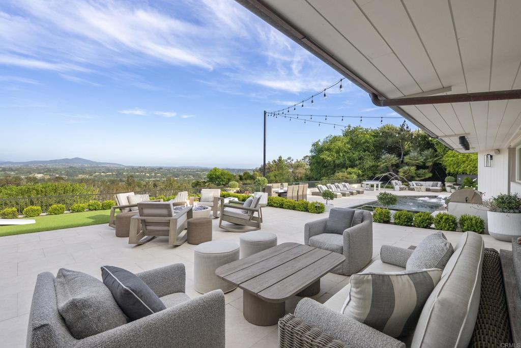Prominently perched on nearly five acres of prime real estate in the heart of Rancho Santa Fe's Covenant neighborhood is a truly unique, expansive view property, thoughtfully named "La Bella Vita,” the good life. Currently the pristine property boasts an ultra-cool fully renovated mid-century modern single level three bedroom plus bonus room, three full bath residence with a modern pool/jacuzzi. This quintessential Ranch & Coast design has been thoughtfully curated with classic and contemporary elements, resulting in a warm, timeless and inviting aesthetic. It's characterized by natural materials, sophisticated silhouettes, and a mix of vintage and modern accents. The design includes high-end zellige tile and marble slab material, Wolf/Subzero/ Cove appliance, Toto toilets and designer lighting throughout. Equipped with Samsung TVs, Sonos indoor/outdoor entertainment and Ring security system the home is both easy to operate and technologically proficient. In addition, this property comes with FULLY APPROVED Art Jury/City plans and reveals a future main house of nearly 12,000 square feet - 6 bedrooms and 7 bathrooms, alongside a separate 1200 sq ft guest house with 1 bedroom and 1 bathroom, and 14 car garage. Curated by designer homeowner, and formulated by John Jensen architects, this designer home is a poetic expression of modern elements and intimate living, ultimately creating a stunning architectural masterpiece. These plans embrace the site's full potential while harmonizing with the surrounding environment that makes Rancho Santa Fe’s Covenant one of a kind. The innovative layout capitalizes on the expansive lot, with a unique orientation that captures breathtaking views.