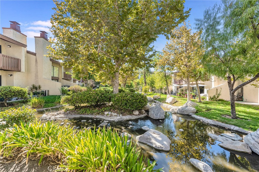 This is the one you’ve been waiting for! Relax on your private back patio while listening to the soothing sound of water flowing through the creek, surrounded by trees and lush grassy areas. This beautifully maintained home features a spacious open floor plan with an updated kitchen, complete with stainless steel appliances, and seamlessly connects to the dining and living areas—perfect for entertaining. Cozy up by the fireplace while enjoying serene views of the water just outside your windows. Downstairs boasts brand-new vinyl flooring and a convenient powder room. Upstairs, you'll find three well-sized bedrooms and two full bathrooms. The large primary suite offers soaring ceilings, a generous walk-in closet, an en suite bath, and a private balcony with tranquil views of the creek, trees, and greenbelt. The additional two bedrooms share a full bath with an updated vanity and a combined shower/tub. A dedicated laundry area with washer and dryer is conveniently located upstairs. The home also includes a private two-car garage. Set within a beautifully landscaped community featuring meandering creeks, two tennis courts, and a resort-style pool and spa area. All of this is ideally located near Warner Center, The Village, Westfield Topanga Mall, and just steps from a vibrant park with summer concerts. Enjoy easy access to incredible restaurants, shopping, and entertainment! Don’t miss this rare opportunity to own a peaceful retreat in the heart of it all!