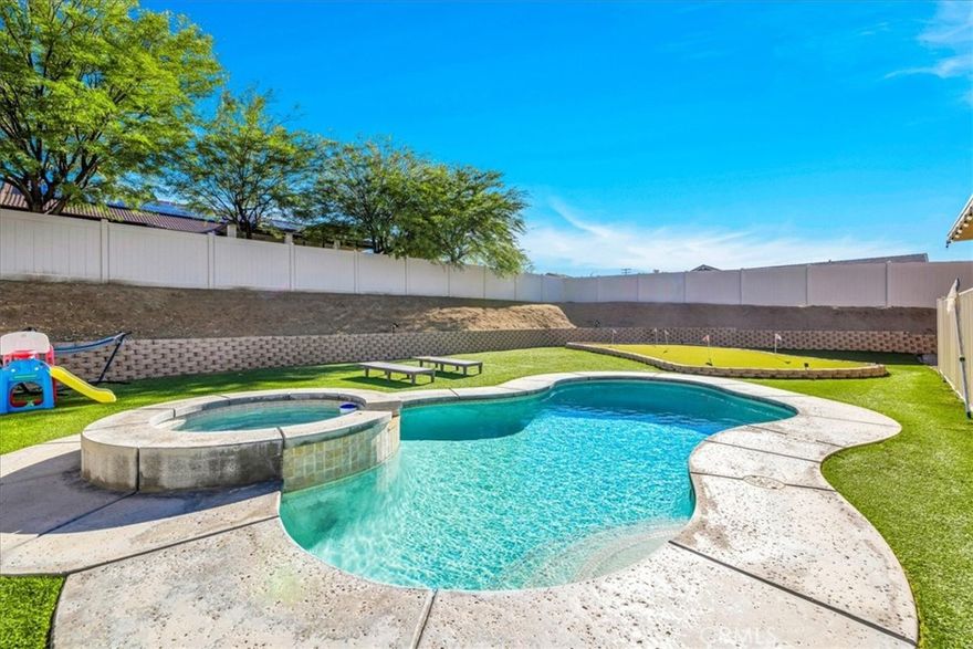 Welcome to 56135 Nez Perce, a stunning turn-key POOL home located in the highly desirable Mesquite neighborhood of Yucca Valley. This beautifully maintained 3 bedroom, 2 bath property is nicely situated on a large corner lot and features 1,764 square feet of living space. As you step inside the bright & airy great room you'll find 10-foot ceilings, earth-toned tile flooring, a lovely gas fireplace and large windows that let in an abundance of natural light. This home's modern style and open-concept layout is one to be desired. The living room flows effortlessly into the dining and kitchen area complete with recessed lighting, upgraded appliances, a center island with beautiful granite countertops and bar seating, ample cabinet & counter space and a walk-in pantry. All bedrooms have carpeted floors & ceiling fans, and the primary bedroom adorns french doors and a sliding glass door that leads to the back patio. The ensuite bathroom is sure to impress with a dual sink vanity, jetted tub, walk-in shower and huge walk-in closet. There is also a convenient indoor laundry room just off the kitchen with a utility sink and additional cabinetry for storage. That's just the inside! The backyard is truly an entertainer's paradise. From the awe-inspiring in-ground pool and spa to the turf putting green, large covered patio with ceiling fans, stucco pergola, Vinyl privacy fencing and ample space for BBQs and get togethers, it's like having a little resort right outside your back door. Not to mention the oversized 3 car garage, low HOA and close proximity to town, schools, shopping, eateries & more! Come take a look & let this homes charming allure do the rest, your new desert home or weekend retreat awaits!