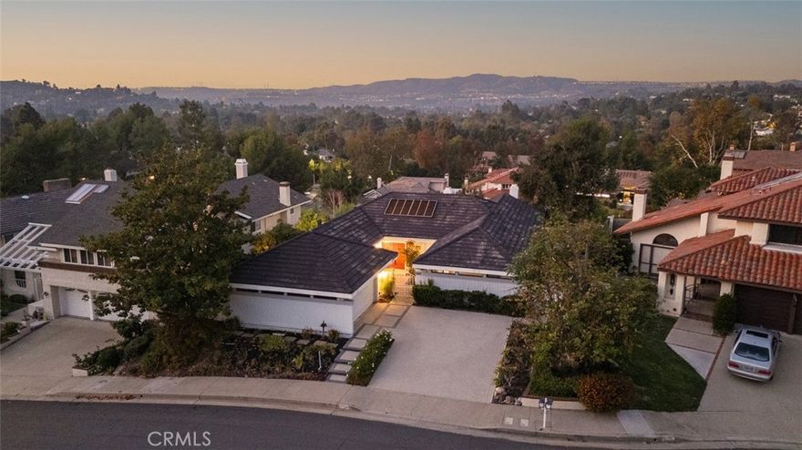 Set on a quiet cul-de-sac in the highly sought-after equestrian community of High Horse Trails in beautiful Orange Park Acres, this single-level residence captures gorgeous panoramic views of the rolling hills and distant San Gabriel Mountains. Just two blocks from community horse trails and stables, the location perfectly balances privacy, tranquility, and an inviting country charm. Inside, you’ll find two spacious bedrooms plus a dedicated office with built-in bookcases and generous storage - easily convertible into a third bedroom. Both en-suite primary retreats offer comfort and flexibility for multi-generational living or guest accommodations. The primary suite features a cozy fireplace, sunrise views with private access to the deck, and a spacious bath with a walk-in shower, pebble stone flooring, Brizio fixtures, and mirrored wardrobe doors. The secondary bedroom opens through French doors to the front courtyard, creating a serene retreat. The entryway and living room impress with cathedral ceilings, a dramatic fireplace, and French doors leading to a generous view deck - ideal for entertaining or simply unwinding while taking in the scenery. The formal dining room connects seamlessly to the bright, cheerful kitchen, which retains its original charm and features oversized windows that flood the space with natural light. The adjacent family room encourages an effortless open-concept flow for everyday living. While some areas would benefit from thoughtful updating, the home is well-maintained, full of character, and easily lived in as-is - inviting you to move in now and personalize over time. Additional highlights include Brazilian cherry wood flooring, an enclosed front courtyard, thriving avocado, Meyer lemon, and orange trees, a dog run, an interlocking paver driveway, and softly lighted steps ascending from the street. This is a unique opportunity to own a single-level view home in one of Orange’s most desirable neighborhoods, where peaceful living meets the convenience and vibrancy of Southern California life.