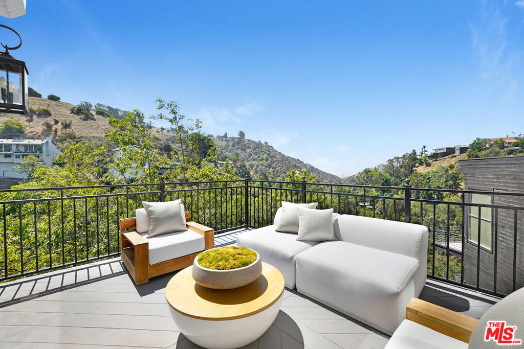 This exceptional retreat offers a main residence and separate self contained unit, making it as versatile as it is stunning. Spectacular 270-degree views and a rare street-to-street double lot set the stage for this meticulously renovated smart home offering privacy and style. The main house offers 3 generous bedrooms, and 2.5 bathrooms. *As a standout, the property includes a modern 1 bed, 1 bath bonus unit* complete with its own private entrance deck, full kitchen with quartz counters, full-size washer & dryer, and custom walk-in closet adding endless possibilities - rental income, a guest suite, or a creative workspace. Inside the main home, no detail was overlooked. Flooded with natural light, the expansive living and dining area seamlessly open to a breathtaking deck, creating the perfect setting for elevated indoor-outdoor living. The chef's kitchen showcases marble counters, custom cabinetry, a full suite of high-end GE Monogram appliances, a built-in refrigerator, two wine refrigerators, and a custom pantry. *The primary retreat features everything you could dream of - Gracie wallpaper, full bathroom with dual sink vanity and contemporary freestanding tub, a walk-in custom closet, an office/nursery, plus a showstopping sunroom with floor to ceiling windows & incredible views from all angles! You will enjoy the engineered wood floors, recessed lighting, custom built-ins, and Restoration Hardware vanities to complete the luxurious feel. Smart features include Nest thermostat, dual-zone HVAC, dual-fuel fireplace, a SimpliSafe security system, Ring cameras, and app-controlled smart timer. Exterior upgrades include a new roof, skylights, chimney mesh, stucco, custom iron railings, and new double-paned windows. The property is enhanced with an app controlled drip irrigation system, gutter guards, and a remote controlled hurricane shutter. A new garage door, locking mailbin, and a custom trash enclosure platform further elevate functionality. The reimagined landscaping in front and back creates tranquil garden spaces, complete with a fruit bearing orange tree, and frames the expansive views that can be enjoyed from nearly every window. The guest unit was sound-insulated with double drywall and cork and features its own deck and entry stairway. Additional highlights include a new Samsung washer and dryer, built-in custom closets, a live-edge wood desk in 1 bedroom, a whole house water filtration system and a tankless water heater. Infrastructure upgrades include a new water regulator, jetted plumbing lines, and an extended clean-out further down the hill. With over 11,000 square feet of land, and a wide street with ample guest parking, this property offers tremendous expansion potential including room to add a pool. Located just minutes from Sunset Blvd with easy access to the Valley via Laurel Canyon, and within walking distance to hiking trails and open space, this is a truly one-of-a-kind opportunity to live above it all. A turnkey hillside retreat with architectural appeal, luxury upgrades, and priceless panoramic views. Broker and agents have not verified the accuracy of square footage, income, expenses, condition, development potential, bedroom/bathroom count, lot size or boundaries, dimensions, permitted or unpermitted areas, or school eligibility. Buyers are encouraged to conduct their own investigations with qualified professionals to confirm all information. No warranties or guarantees are being made buyers should rely on their own inspections and due diligence. Some view photos have been enlarged to better showcase specific features.