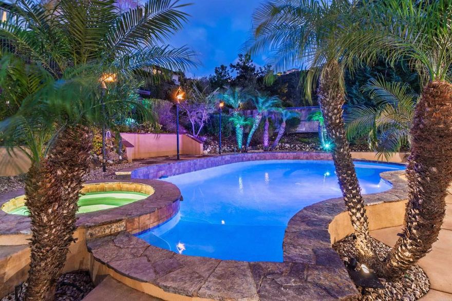 Welcome to 1459 Lighthouse Rd, an exceptional Westcliffe residence in the heart of San Elijo Hills, offering the ultimate blend of luxury, comfort, and California indoor-outdoor living. Located in a premium gated community, this home sits on an expansive 11,743 sq ft lot and delivers an impeccable layout with 4 bedrooms, a large dedicated office, a true downstairs movie theater with reclining seating, an upstairs loft, and a spacious 3-car garage—all wrapped into a fabulous, highly functional floorplan.  Thoughtful upgrades shine throughout, including high-mil vinyl flooring, new lower-level HVAC, garage mini-split AC, and a 55-panel owned solar system for outstanding energy efficiency.  At the heart of the home, the beautifully appointed kitchen opens seamlessly to the cozy den with a fireplace—creating the perfect space for gatherings, conversations, and everyday living. The kitchen features dual ovens, a built-in Monogram refrigerator, sleek black stainless steel appliances, a beverage fridge, a large island with seating, and a walk-in pantry. It’s a warm, social hub designed for both functionality and style.  There is a spacious laundry room downstairs, and for added convenience, a laundry chute from the upper level drops directly into it—making busy days easier and keeping everything effortlessly organized.  From the main living areas, double French doors lead straight to your private backyard oasis—an entertainer’s dream designed for year-round enjoyment. The resort-style outdoor space features a sparkling pool, spa, gas fire pit, built-in tiki torches, and a built-in BBQ, all surrounded by generous patio spaces perfect for relaxing or hosting. Pool equipment has been fully modernized with app-based controllers and a new high-efficiency heater, while a smart sprinkler system and a Tesla electric car charger add everyday convenience.  Upstairs, the expansive primary suite serves as a true retreat, offering a large en suite bathroom with a deep built-in soaking tub, dual sinks and vanities, and a very large walk-in closet. One of the additional bedrooms functions as a junior suite, offering enough space for a sitting area—or even the potential for a future kitchenette—making it ideal for multi-generational living, long-term guests, or an elevated private hideaway. The loft adds flexibility as a lounge, study area, or play zone.  Downstairs, the dedicated movie theater provides the perfect space for immersive viewing, while the oversized office offers room to work, create, or study without compromise.  Situated in the coveted community of San Elijo Hills, residents enjoy beautifully maintained hiking and biking trails, scenic viewpoints, friendly neighbors, and a charming town center filled with shops, restaurants, and community events. Highly rated schools and several parks are just down the block, making this one of North County’s most beloved master-planned neighborhoods.