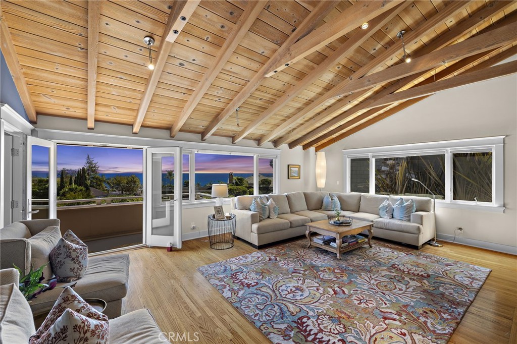 Nestled in the coveted Tree Streets of North Laguna, this beautifully appointed residence offers sweeping ocean and Catalina Island views from nearly every angle. With three en suite bedrooms and a layout designed for seamless indoor-outdoor living, the home blends classic charm with elevated coastal style. The main living room is warm and inviting, featuring soaring wood-beamed ceilings, oak flooring, a floor-to-ceiling brick fireplace, and oversized windows that frame the breathtaking views. Just off the living room, an expansive balcony provides the perfect setting for sunset watching or morning coffee by the sea. Open to the living space, the kitchen and dining area are designed with both style and function in mind—featuring high-end stainless appliances including a Viking stove, granite countertops with a breakfast bar, a second brick fireplace, and vaulted ceilings with a skylight providing abundant natural light. French doors from the dining area lead to a terraced garden oasis complete with multiple sitting areas, an upper deck with incredible views, and mature landscaping that includes lemon, orange, olive, and magnolia trees. All three bedrooms are en suite, with beautifully finished bathrooms. The primary suite stands out with its ocean views that make every morning feel like a retreat. Located in sought-after North Laguna, just blocks from world-renowned beaches, art galleries, upscale dining, and boutique shops, this home offers the best of Laguna Beach living in one of its most desirable neighborhoods.