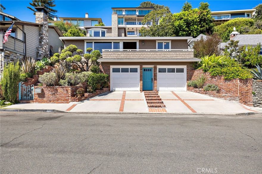 Nestled in the coveted Tree Streets of North Laguna, this beautifully appointed residence offers sweeping ocean and Catalina Island views from nearly every angle. With three en suite bedrooms and a layout designed for seamless indoor-outdoor living, the home blends classic charm with elevated coastal style. The main living room is warm and inviting, featuring soaring wood-beamed ceilings, oak flooring, a floor-to-ceiling brick fireplace, and oversized windows that frame the breathtaking views. Just off the living room, an expansive balcony provides the perfect setting for sunset watching or morning coffee by the sea. Open to the living space, the kitchen and dining area are designed with both style and function in mind—featuring high-end stainless appliances including a Viking stove, granite countertops with a breakfast bar, a second brick fireplace, and vaulted ceilings with a skylight providing abundant natural light. French doors from the dining area lead to a terraced garden oasis complete with multiple sitting areas, an upper deck with incredible views, and mature landscaping that includes lemon, orange, olive, and magnolia trees. All three bedrooms are en suite, with beautifully finished bathrooms. The primary suite stands out with its ocean views that make every morning feel like a retreat. Located in sought-after North Laguna, just blocks from world-renowned beaches, art galleries, upscale dining, and boutique shops, this home offers the best of Laguna Beach living in one of its most desirable neighborhoods.
