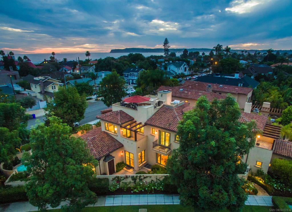 Step into your private sanctuary at this extraordinary compound, perfectly positioned on a rare corner lot in the heart of Coronado. Just one block from Center Beach and the iconic Hotel Del Coronado, this distinguished residence is a true architectural showpiece—designed by Dorothy Howard and constructed by Papenhausen Construction—where timeless elegance meets exceptional craftsmanship. Exuding classic Mediterranean charm, the home is richly appointed with an exquisite blend of natural stones, marbles, and granites. The interiors are grand yet inviting, featuring soaring vaulted ceilings with vintage timber beams, custom cabinetry, and crystal chandeliers that lend warmth and sophistication to every space. Encompassing approximately 5,400 square feet, this one-of-a-kind property offers a thoughtfully designed floor plan ideal for both relaxed living and entertaining. The primary suite serves as a luxurious retreat with a spa-style bathroom, complemented by three additional en-suite bedrooms. The expansive great room is perfect for family gatherings, while the custom-paneled executive office, temperature-controlled wine cellar, private theater, and serene outdoor spa create a resort-like experience at home. The professionally landscaped yard provides a tranquil garden setting for relaxation or entertaining. Rooftop deck offers sweeping views and the ideal backdrop for sunset cocktails or evening BBQs. Modern features including an elevator, Lutron lighting system, central vacuum, storage room, and a three-car garage ensure comfort and convenience at every turn. This exceptional home is ideally located for those seeking both privacy and proximity—just steps from the beach, restaurants, shops, and the vibrant lifestyle of Coronado Village. A rare opportunity to own a legacy property in one of California’s most prestigious coastal communities.