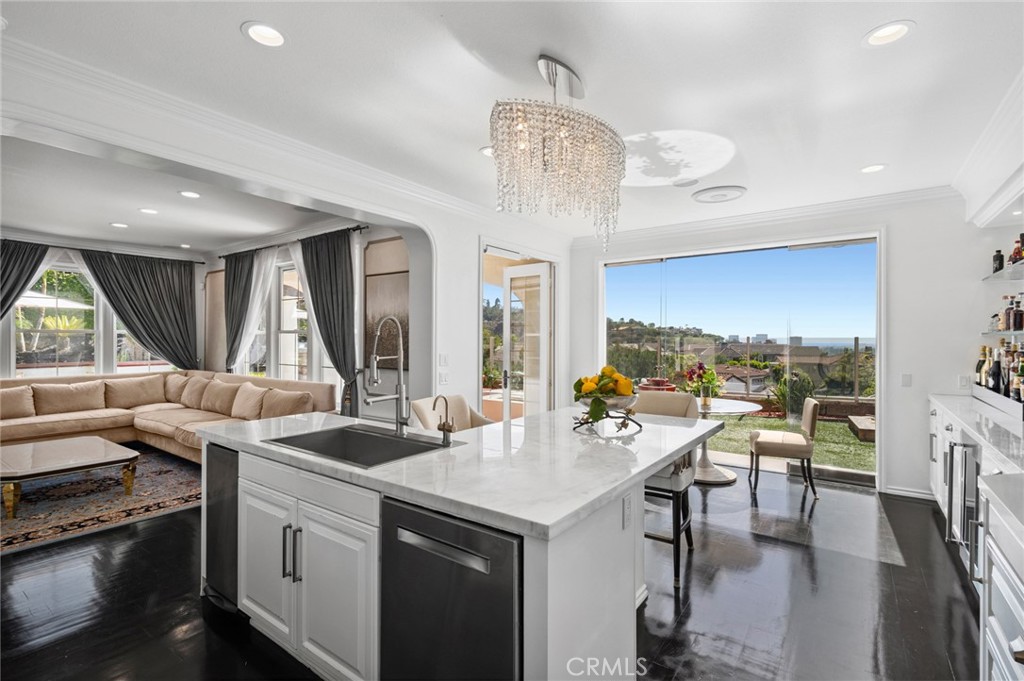Indulge in the serenity of elevated ocean-view living in Newport Coast at this exceptionally private estate, nestled on an oversized lot behind the guarded gates of Newport Ridge North. Thoughtfully upgraded, this refined residence captures breathtaking vistas of the Pacific Ocean, coastline and sparkling city lights. Set on a tranquil cul-de-sac with approximately 9,322 square feet of private grounds, the property offers a rare opportunity to enjoy sophisticated resort-style living. The interiors are as impressive in size as they are in design, encompassing nearly 4,432 sqft. of curated living space. Crafted for seamless indoor-outdoor living, the home features 5 ensuite bedrooms, including a main-level guest suite with separate access, and 5.5 opulent baths, ensuring comfort and flexibility. Entertaining is effortless with formal spaces complemented by an executive-style office on the main level, and an all-season loggia that opens to the outdoors—ideal as a game room, lounge, or additional gathering space. The chef-caliber kitchen is appointed with custom cabinetry, marble countertops, premium appliances, and a striking built-in bar. An oversized eat-in island anchors the space and flows seamlessly into the family room and expansive backyard. The backyard is a sanctuary featuring tranquil water features, outdoor kitchen with built-in BBQ, and multiple spaces designed for entertaining and relaxation. Upstairs, the primary suite serves as a peaceful retreat, offering sweeping ocean and city-light views. Enjoy a cozy fireplace, boutique-style walk-in closet with illuminated custom built-ins, and a spa-inspired primary bath with dual vanities, a soaking tub, walk-in shower, and a secondary walk-in closet. A private balcony invites you to take in panoramic views—perfect for morning coffee or sunset reflections. Designed for both intimate moments and larger gatherings, the estate also includes a detached suite offering flexible living arrangements. An oversized two-car garage with built-in workspace enhances everyday functionality. The community’s prime location provides access to resort-style amenities including a clubhouse, pool and spa, sports courts, parks, and playgrounds—all within an exclusive and meticulously maintained setting. With dual gated entrances, you’ll enjoy easy proximity to world-class shopping, fine dining, top-rated schools, scenic trails, pristine beaches, and John Wayne Airport. This is Newport Coast living at its finest.