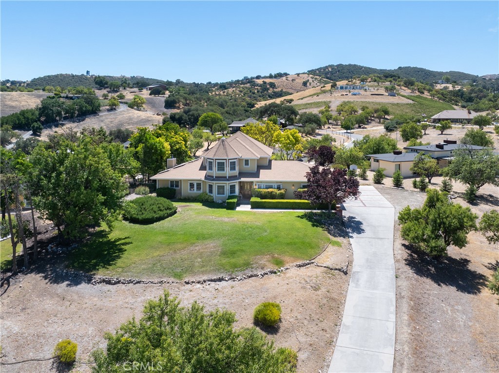 Perched atop an almond-studded knoll just moments from downtown Paso Robles, this enchanting custom residence offers nearly an acre of privacy, panoramic views, and a location within walking distance of acclaimed restaurants, tasting rooms, and entertainment. A newer roof, owned solar, and timeless architectural details enhance its enduring appeal. Inside, the main level features a newly carpeted primary suite, private office, and multiple gathering spaces, including a formal dining room, family room, and living room. Upstairs, three spacious guest bedrooms, two full bathrooms, and a charming west-facing balcony capture sweeping vistas. Completing the property is a generous three-car garage, offering abundant space for vehicles, storage, or workshop use—seamlessly blending elegance, comfort, and practicality.