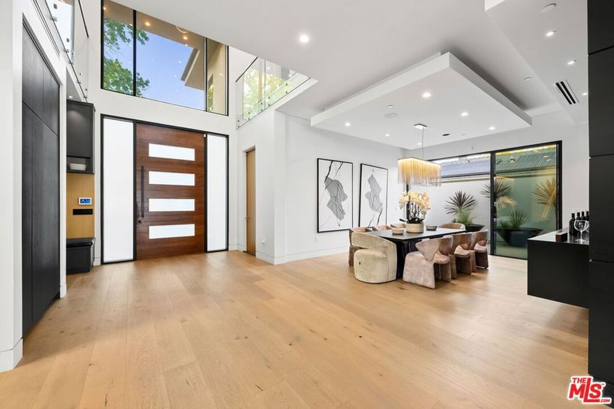 A rare gem nestled on an expansive, nearly 10,000 sq ft flat lot in the highly sought-after Sherman Oaks neighborhood. This stunning Modern Architectural Estate sits on an extra-wide parcel, surrounded by thoughtfully designed landscaping and mature trees. A striking 10-foot entry door welcomes you into soaring ceilings and an open-concept layout adorned with expansive walls of glass, wide-plank European oak flooring, and a custom floating glass staircase. The formal dining room boasts a built-in buffet, paneled walls, a floating ceiling, and sliding glass doors that open to the outdoors. A dramatic living room is centered around a sleek marble slab fireplace, while the state-of-the-art gourmet kitchen features custom cabinetry, quartz countertops, top-of-the-line appliances, and dual islands perfect for entertaining. Cortizo glass pocket doors blur the lines between indoor and outdoor living, leading to a true entertainer's dream: a resort-style backyard complete with a zero-edge pool and spa, fire pit, and a pool house with a full bath. The luxurious primary suite offers a cozy fireplace, private balcony, spacious walk-in closet, and a spa-inspired bathroom. Additional features include electric blinds, a smart home system, custom lighting, and a security system with cameras. Designed with quality craftsmanship and meticulous attention to detail, this home is ideal for both grand entertaining and intimate gatherings.
