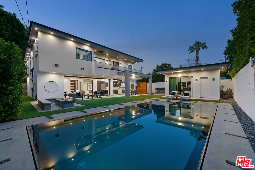A rare gem nestled on an expansive, nearly 10,000 sq ft flat lot in the highly sought-after Sherman Oaks neighborhood. This stunning Modern Architectural Estate sits on an extra-wide parcel, surrounded by thoughtfully designed landscaping and mature trees. A striking 10-foot entry door welcomes you into soaring ceilings and an open-concept layout adorned with expansive walls of glass, wide-plank European oak flooring, and a custom floating glass staircase. The formal dining room boasts a built-in buffet, paneled walls, a floating ceiling, and sliding glass doors that open to the outdoors. A dramatic living room is centered around a sleek marble slab fireplace, while the state-of-the-art gourmet kitchen features custom cabinetry, quartz countertops, top-of-the-line appliances, and dual islands perfect for entertaining. Cortizo glass pocket doors blur the lines between indoor and outdoor living, leading to a true entertainer's dream: a resort-style backyard complete with a zero-edge pool and spa, fire pit, and a pool house with a full bath. The luxurious primary suite offers a cozy fireplace, private balcony, spacious walk-in closet, and a spa-inspired bathroom. Additional features include electric blinds, a smart home system, custom lighting, and a security system with cameras. Designed with quality craftsmanship and meticulous attention to detail, this home is ideal for both grand entertaining and intimate gatherings.