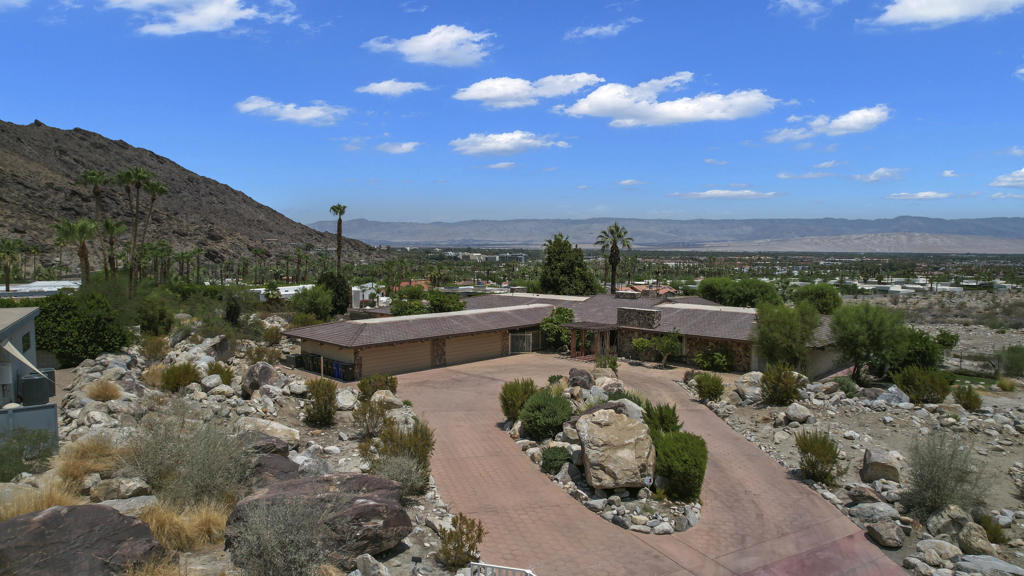 This may be your last chance to have a true (3.9 acres) South Palm Springs Estate .Enter thru an electric gate to the circular driveway and into one of your 2 double car garages Double Doors take to the entry with soaring ceilings and a wonderful sense of arrival as you look past the giant stone see thru fireplace to the gracious step down living room with wall to wall glass-Views ! Views! and more Views! This one of a kind property is nestled in the rocks and hillside. The guest or family wing includes 4 bedrooms and 4.5 baths with an oversized family room- all ensuite with large or walk-in closets and valley views. One suite even has small kitchenette. The primary wing includes its own sitting room, a walk- in closet over 600 sq ft and separate office area. with more beautiful Valley views. The Kitchen with large great room has another wall of glass and easy access to the mosaic pool and North South tennis court (in excellent condition). The lower level includes a large covered patio and pool ''house'' with kitchen, bath and room with closet plus additional room for storage or?This area could also be nice guest quarters. It opens to an expansive grassy areas just steps to the pool and a short walk to the tennis court . The whole outdoor area is perfect for entertaining on a very grand scale. This is a one of a kind property with few like it in Palm Springs, It is in original condition but the possibilities are endless.Property is currently being surveyed so boundaries will be clear.