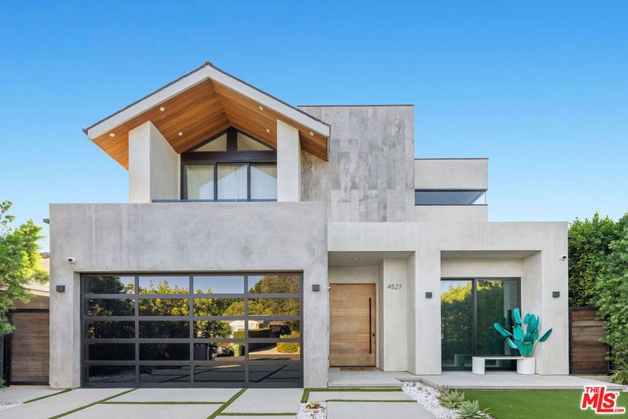 Located on a quiet street in Studio City, this stunning contemporary residence is privately nestled behind gates and mature hedges. Spanning almost 4,000 square feet, the 4-bed, 5-bath home showcases clean lines, curated materials, and high-end finishes throughout. Designed with both comfort and entertaining in mind, the main level features expansive living, dining, and kitchen areas that flow seamlessly outdoors through oversized aluminum sliding glass doors. Soaring ceilings, sleek fixtures, and designer details create a refined yet welcoming ambiance. The gourmet kitchen is equipped with premium appliances, custom cabinetry, a large island, and an adjoining breakfast nook. Upstairs, the primary suite offers a spacious walk-in closet, balcony lounge, and spa-like bath with a steam shower, Italian-designed vanities, and a dedicated make-up vanity. A water softener system enhances daily living by filtering out hard metals to nourish skin and hair. Each additional bedroom includes its own en-suite bath and generous proportions, ensuring both privacy and luxury for family and guests. The private backyard oasis is ideal for entertaining, complete with a sparkling pool and spa, built-in BBQ, low-maintenance turf, and multiple lounge areas. The home is fully outfitted as a smart residence, with integrated controls for music, lighting, spa, climate, and security systems. Located within the top-rated Colfax School District and just moments from shops, restaurants, and the newly opened Sportsmen's Lodge, this residence perfectly blends modern design, functionality, and convenience.