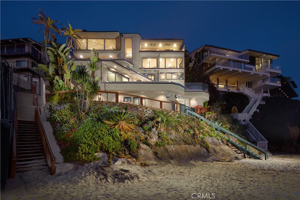 Beyond the gates of Lagunita, this stunning estate overlooks the pristine sands and turquoise waters of Victoria Beach. Sweeping views unfold from nearly every room, showcasing dramatic cliffs and the secluded beauty of Laguna’s coastline. Designed for ultimate privacy, the residence features exclusive beach access via rare private stairs and an impressive 66 feet of ocean frontage. Soaring vaulted ceilings, a stately fireplace, and floor-to-ceiling glass frame Catalina Island in the distance, making the formal living room a captivating space. Outfitted with SubZero, Viking, Thermador, and Miele appliances, the gourmet chef’s kitchen spills onto a sun-drenched terrace, inviting alfresco dining against the rhythmic backdrop of the waves.
An elevated sense of retreat defines the primary suite, where a cozy fireplace, an ocean-view gym with a dry sauna and steam room, and a private terrace create an escape rivaling the world’s finest resorts. Indulgence continues in the custom walk-in closet, enhanced by LED lighting. Three generous guest suites extend onto a vast deck overlooking the beach, each adorned with designer wallpaper. Newly remodeled decks strengthen the home's connection to the coastal landscape, offering refreshed spaces for lounging, entertaining, and soaking in the panoramic ocean views.
Luxury extends to every detail, including a fully built-out office and an elevator servicing all levels. Glass-railing staircases descend to the lower level, revealing a media room with a wet bar and projector, designed for refined relaxation. A sleek wet bar and striking designer lighting set the tone in the game room, a perfect space for recreation and entertainment.
Further along, a 1,000-bottle wine room leads to a sprawling deck with a sparkling outdoor spa, ideal for intimate gatherings under the stars. On the lowest level, an ADU boasts a kitchenette, full bath, and unique built-in sleeping loft—offering a stylish and functional retreat by the shore.
Completing this coastal sanctuary, a three-car garage and private beach access enhance the seamless blend of exclusivity and convenience. Ideally situated between Laguna’s iconic Pirate’s Tower and the renowned Montage Resort, this coastal retreat embodies the perfect balance of serenity and sophistication.