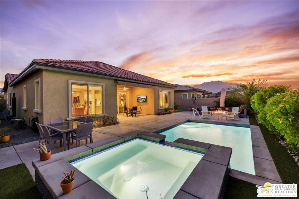 Welcome to a truly exceptional residence in the prestigious Del Webb Rancho Mirage community. This rare PHASE 5, PLAN 7 REFUGE offers dual primary suites, a versatile flex space, and a coveted powder room, all designed with sophistication and comfort in mind. Step inside and discover thoughtfully curated designer finishes throughout, including 12x24" porcelain tile, custom window treatments, and refined architectural details. The gourmet kitchen is a chef's delight with upgraded 42" upper cabinets crowned with molding, sleek quartz countertops with full backsplash, dual ovens, and an oversized island illuminated by hand-selected pendant lighting - perfect for entertaining. The expansive great room features the rare wet bar option, complete with wine fridge, and seamlessly connects to the outdoors through three-panel sliding glass doors. Step into your private desert retreat where a covered patio, remote-powered retractable awning, custom saltwater pool and spa, gas fire pit, and panoramic mountain views await. The luxurious primary suite offers serene views of the custom-landscaped backyard and includes a spa-inspired bath with a frameless glass rain shower and abundant closet space. A second primary suite, positioned at the opposite end of the home, ensures ultimate privacy for guests and includes its own beautifully appointed ensuite bathroom. The versatile flex space adapts to your lifestyle - whether you envision a media room, home office, yoga retreat, or a third bedroom thanks to its walk-in closet. Additional highlights include OWNED SOLAR, a generous laundry room with utility sink, oversized climate-controlled garage, water softening system with reverse osmosis, and countless thoughtful upgrades. As a resident of Del Webb, you'll also enjoy access to resort-style amenities including the clubhouse with billiards and bar, state-of-the-art fitness center, tennis, pickleball, bocce ball, and vibrant community events. This home perfectly blends elegance, function, and resort living - an opportunity not to be missed.