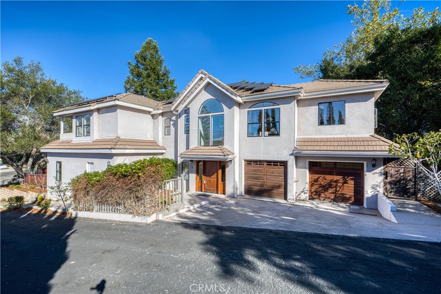 Located on a quiet cul-de-sac in San Luis Obispo’s desirable Banana Belt, known for its mild year-round climate, this spacious 5-bedroom, 3.5-bath home offers 2,914 sq. ft. of comfortable living space. The main level features four bedrooms, including a primary suite with en-suite bath and direct access to the patio and backyard. This versatile suite could also be utilized as a family room, providing an additional gathering space. One of the bedrooms has its own private entrance, making it ideal for a home office or guest quarters. A full hall bath, laundry room, and access to the two-car garage complete this level. Up the sweeping staircase, the bright and inviting upper floor offers a spacious living room with a fireplace and French doors opening to a deck, a dining area, and a well-appointed kitchen with a center island, abundant counter and cabinet space, and a cozy breakfast nook. The upstairs primary suite boasts its own private deck along with a luxurious bath featuring a spa tub and separate shower. Thoughtful details add to the home’s appeal, including owned solar panels for energy efficiency and a convenient second staircase that connects the kitchen directly to the 2 car garage. Set on a generous 10,454 sq. ft. lot, the property is designed for both relaxation and entertaining with multiple decks and seating areas, a putting green, and room for a vegetable garden. The landscaping showcases stately oak and redwood trees, a variety of fruit trees, and even a seasonal creek, creating a private and picturesque setting. All just minutes from downtown San Luis Obispo with its fine dining, unique shops, and the popular Thursday night Farmers’ Market.