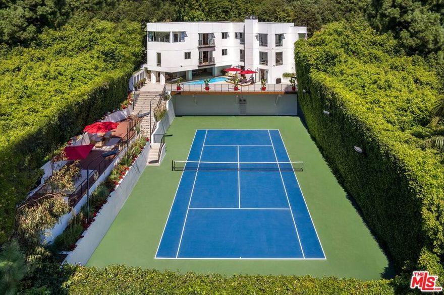 Set behind gates in the exclusive Bird Streets, Warbler Way is a .57-acre tennis court compound where architectural sophistication meets resort-style living. Bold and timeless, this modern masterpiece blends luxurious comfort with sleek design and total privacy. Walls of glass frame sweeping views of the hills and city skyline, while natural light floods the open interiors finished in new organic modern wood floors and curated details throughout. The 4-bedroom residence spans 6,200 square feet with an open-concept layout that includes a gourmet kitchen with Sub-Zero and Viking appliances and an elegant center island, a dining area, and an expansive living room. Amenities include a 12-seat movie theater, full gym, game room with locker and steam, office, maid's quarters, and an additional lower-level family room. A detached guesthouse features a private entrance, walls of glass showcasing sweeping views, and a kitchen and bath perfect for visitors, extended stays, or a serene retreat. The grounds are designed for effortless entertaining, showcasing lush new landscaping, dramatic lighting, a resort-style pool with streaming fountains, BBQ deck, outdoor fireplace, and a newly resurfaced tennis court with lights for night play. Parking includes a 3-car garage plus ample room for 5 additional cars, and 2 guest parking spots above. Just off Doheny and the Sunset Strip, and moments from Beverly Hills, this gated estate is a rare offering an architectural sanctuary where design, luxury, and location converge at the height of Los Angeles living.