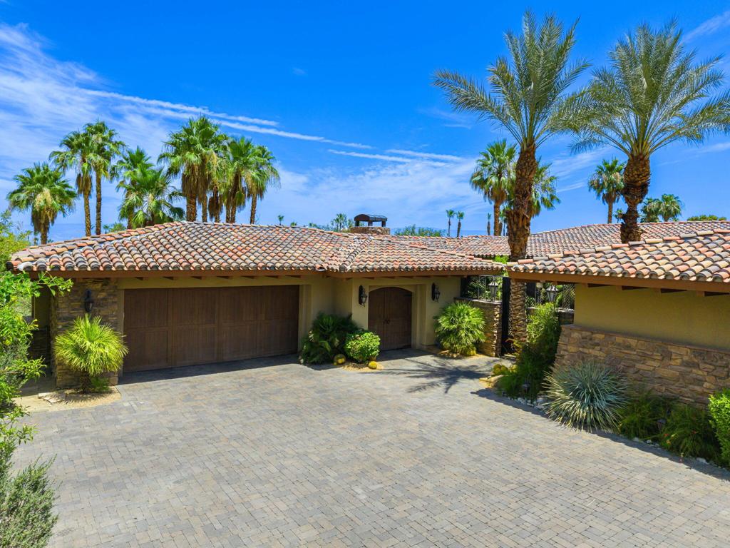This extraordinary estate in the prestigious Canyon View Estates at Ironwood Country Club seamlessly blends refined architecture, cutting-edge innovation, and stunning natural beauty. Perfectly situated along the 16th fairway, the custom residence offers sweeping mountain and river feature views, exemplifying elevated desert living at its finest.Soaring wood-beamed vaulted ceilings and a dramatic fireplace anchor the expansive living area, flowing effortlessly into the resort-style outdoor space. Seamlessly blending indoor-outdoor living, the saltwater pool and spa features elegant deck jets, 30 LED color settings, water fountain features, and an integrated misting system for year-round enjoyment.The outdoor kitchen is fully equipped for grand-scale entertaining, while indoors, two 100-bottle wine refrigerators cradle your finest vintages. A stunning illuminated onyx bar adds the perfect glow to cocktail hour under the stars.The home boasts a wonderfully spacious kitchen featuring stainless steel appliances, including a double oven, two large Sub-Zero refrigerators, 3 stoves, 3 dishwashers, a large breakfast bar, abundant cabinet storage, and granite countertops. Four spacious en-suite bedrooms offer restful privacy, and the primary bedroom is a serene sanctuary. A vaulted climate-controlled bonus room that provides the ideal space to store valuable collections or create a private fitness studio. The laundry room features two sets of stackable washer and dryers for ultimate convenience. Car enthusiasts will appreciate the two fully climate-controlled 2-car garages, each with its own golf cart bay, outfitted with mini-split systems, epoxy flooring, and built-in cabinetry--designed to accommodate and protect your most prized vehicles. Eight total air conditioning zones, whole-home indoor-outdoor surround sound, and remote-controlled lighting deliver smart comfort throughout. Located just minutes El Paseo and The Living Desert. HOA dues are $599 per month.