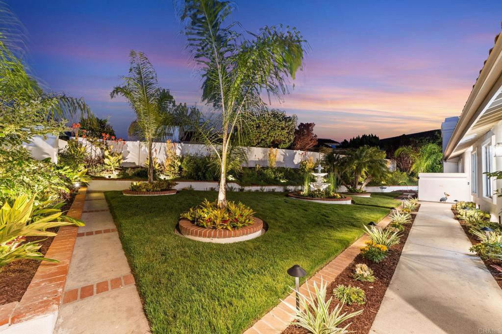 ABSOLUTELY STUNNING COASTAL ELEGANCE: COMPLETELY REVITALIZED RETREAT! NO EXPENSE SPARED! St. Tropez Model. 2 Beds | 2 Baths | Office | One of the Largest, Most Beautiful Yards in the OHCC Community. Welcome to your very own Oasis in the heart of Oceanside! This remarkable property has been revitalized into a glamorous showstopper, blending luxury, modern comfort, and timeless coastal charm. Your Private Shangri-La Awaits—From the moment you arrive, you're greeted by one of the most captivating front yards in the area--Set on an expansive 84’ x 102’ lot, this lush tropical paradise features: • A stunning array of mature tropical palms, vibrant flowers, and succulents • A grand centerpiece fountain • Cooling (pool-sized!) lush green lawn • Raised vinyl privacy fencing for total seclusion • Recently showcased on the Garden Tour, this space is not only serene, but truly extraordinary! • HOA maintains the front yard Interior Elegance & Open Concept Living Inside, natural light floods this fully reimagined open floor plan with panoramic garden views from every window—blurring the lines between indoor luxury and outdoor beauty. A central atrium adds to the peaceful ambiance. The living room is anchored by a bold black beam, modern fan, and striking chandelier, adding depth and drama to the vaulted ceiling. Relax in front of the new floor-to-ceiling stacked stone gas fireplace. The Kitchen Steals the Show: Entertain in style with this chef-inspired masterpiece: • Oversized 8’ island topped with glowing translucent quartzite • Stainless steel appliances & sleek white shaker cabinets • Slide-in gas range with custom hood • Single basin white ceramic sink • Recessed & under-cabinet lighting • Custom layout with incredible flow & functionality Luxury Retreat-Style Primary Suite The spacious primary suite is a tranquil haven, featuring: • Dramatic ceilings with a black beam & modern fan • Peaceful garden views • Huge walk-in custom closet • Spa-inspired ensuite with oversized marble-look shower, bench seat, glass doors, and a double-sink vanity with designer lighting More than Just a Bedroom: The sunny second bedroom overlooks the fountain through two corner windows—guests won’t want to leave! The hall bath is equally refined with: • Deep soaking tub • Rain shower head + handheld spray • Marble-look tile & elegant finishes Community Living at Its Best! Located in a vibrant 55+ community offering: • 18-hole executive golf course with no green fees • Jr. Olympic saltwater pool • Fitness center, 40+ social clubs & events • Activities include crafts, cards, billiards, art, SAILING & RV clubs, RV parking • All for incredibly $10-$15 yearly low fees! Nearly Everything is New • Newer HVAC • Newer Copper Plumbing Throughout • Fresh custom interior & exterior paint • Commercial-grade “beachy” luxury vinyl plank floors • Custom lighting & finishes throughout Live the Coastal Lifestyle Without Lifting a Finger--This home is more than just move-in ready—it’s an elevated way of life in a community where it feels like the cruise ship never leaves the dock. Don't miss your chance to own one of the most breathtaking and unique homes in Ocean Hills Country Club.