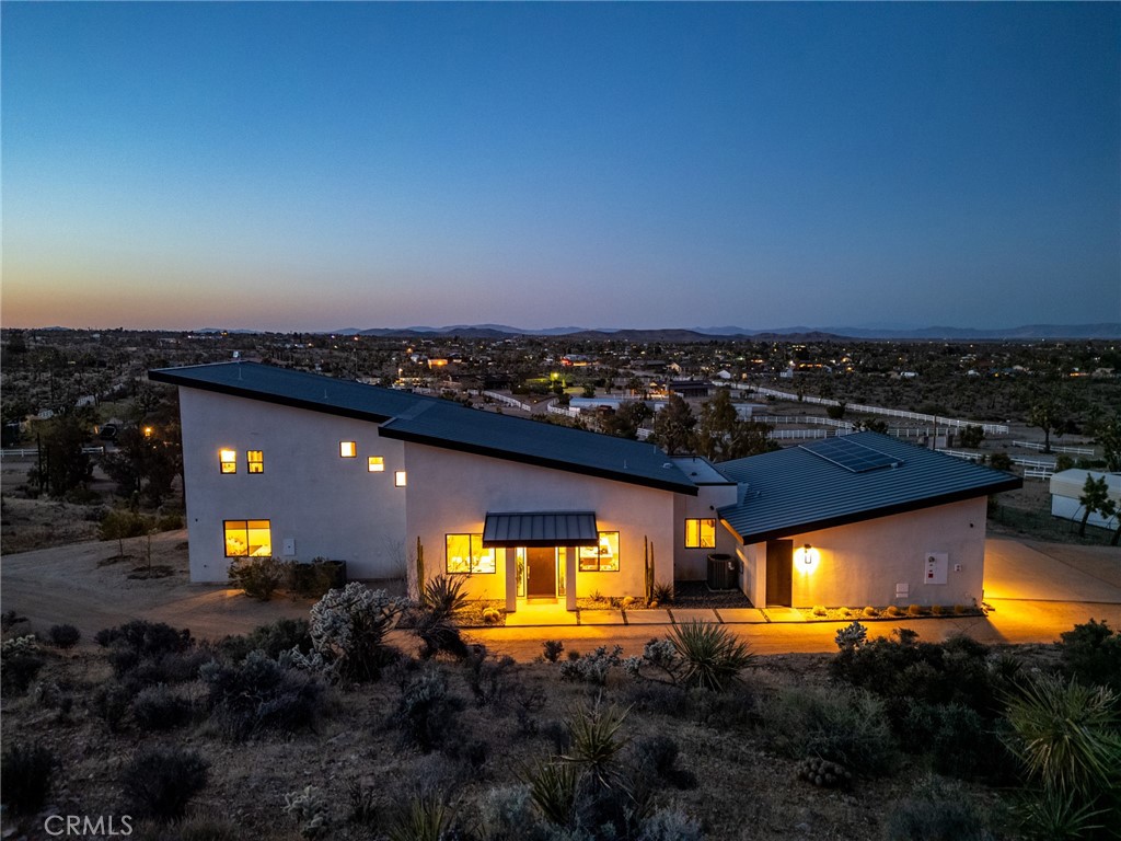 Here's a stunning desert estate, thoughtfully designed to blend modern architecture with the rugged beauty of its natural desert surroundings. Inside, an open-concept floor plan is awash in natural light, featuring clean lines and upscale finishes throughout. The sleek modern kitchen is outfitted with stone countertops, custom cabinetry, an integrated refrigerator, and top-tier appliances.
The kitchen, dining, and living areas seamlessly flow together, all oriented toward panoramic sliding doors that frame expansive desert views to the north. Throughout the main level natural wood accents, black steel fixtures, and polished concrete floors establish a theme of refined, uncomplicated elegance, while each bathroom introduces a touch of contrast with copper fixtures, stylish deco and Marin tile backsplashes.
Upstairs, a balcony overlooks the main living space and leads to the spacious primary bedroom, complete with a private bathroom, walk-in closet, and its own outdoor balcony to further soak in the surrounding desert vistas.
Step outside and you'll find a sparkling pool and spa just beyond the main living area—perfect for indoor-outdoor entertaining. The outdoor space also includes a BBQ area and a built-in fire pit, ideal for relaxing under star-studded desert night skies.
Tech-savvy folks will appreciate this Smart Home is equipped with whole-home audio, high-speed internet, and a security camera system. Ideally located just minutes from eclectic local shops, dining, Joshua Tree National Park, and Pioneertown. This home is a must-see to truly appreciate!