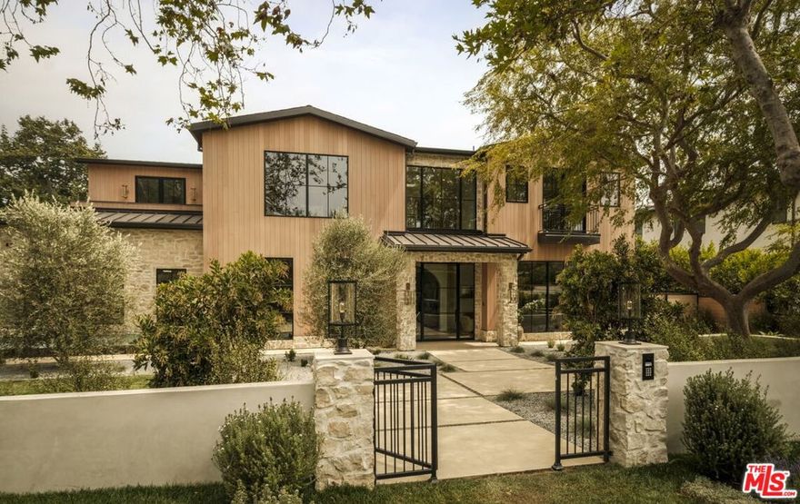 Mediterranean charm meets refined European elegance in this brand-new construction, 6-bedroom plus office, 9-bath, 10,100 sq ft residence set on a 14,143 sq ft corner lot. Heritage olive trees, vintage ceramic pots, and lush Mediterranean-inspired gardens frame a tumbled natural stone facade accented with fire-rated Acre siding that blends durability with timeless appeal. Step inside to discover interiors that celebrate artisanal craftsmanship and understated luxury. Solid white oak floors flow seamlessly throughout, complemented by intricate custom wood moldings and millwork that bring depth and warmth to every room. A curated selection of handpicked designer finishes lends effortless sophistication. The chef's kitchen features custom marble countertops sourced and designed with inspiration from classic French ateliers, paired with European checkered flooring that continues into the hidden butler's pantry. Formal living and dining rooms, a family room, and multiple entertaining spaces connect effortlessly to the resort-style backyard. Outdoors, a shimmering pool and spa with checkered stone waterline tiles set the tone for a luxurious living experience. An outdoor kitchen featuring an Alfresco pizza oven, a sculptural fire pit, and multiple terraces with panoramic canyon views extends the living space beyond the interior. The primary suite offers a tranquil escape beneath vaulted white oak ceilings, complete with dual walk-in closets, a private morning bar, and a spa-like bath featuring Waterworks fixtures and a Hydro Systems soaking tub . Additional amenities include a moody speakeasy bar, a 1,657-bottle refrigerated wine room, a state-of-the-art theater, and a wellness wing with a gym, cold plunge, sauna, steam room, and private massage room.