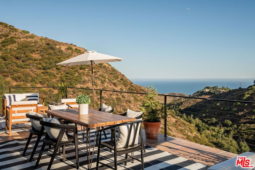 Tucked away on two beautifully landscaped lots totaling almost half an acre, this updated ocean-view retreat evokes the feel of a private Spanish villa, just 15 minutes from Malibu Country Mart and Zuma Beach. This 5-bedroom + detached office bungalow, 3-bathroom residence spans three light-filled stories, offering a harmonious blend of curated interiors, open flow, and tranquil spaces tailored for relaxed coastal living. Perfect for those seeking a slower pace and scenic surroundings, this remodeled property features refreshed landscaping and interiors filled with natural light, tile flooring, and custom finishes throughout. Off the main level, a beautiful ocean-view deck invites effortless indoor-outdoor living and entertaining as well as cosy corners for reading or work. Upstairs, the primary ensuite features a walk-in closet and a balcony escape well-suited for morning coffee with a view. Two additional bedrooms with a bathroom complete the upper level, along with another balcony that captures the surrounding beauty. Downstairs, two more rooms and a den add flexibility for use as guest rooms, offices or gyms. Additionally, a completely covered patio downstairs with beautiful views gives you another option to enjoy your beautiful surroundings. Lastly, past the manicured lawn, a quaint bungalow provides an incredible office space. Completely move-in-ready with sweeping views of the Pacific Ocean and Santa Monica Mountains, this is an ideal haven for anyone craving beauty, privacy, peace, and the finest of Malibu living, just 13 minutes from the nearest shopping center.