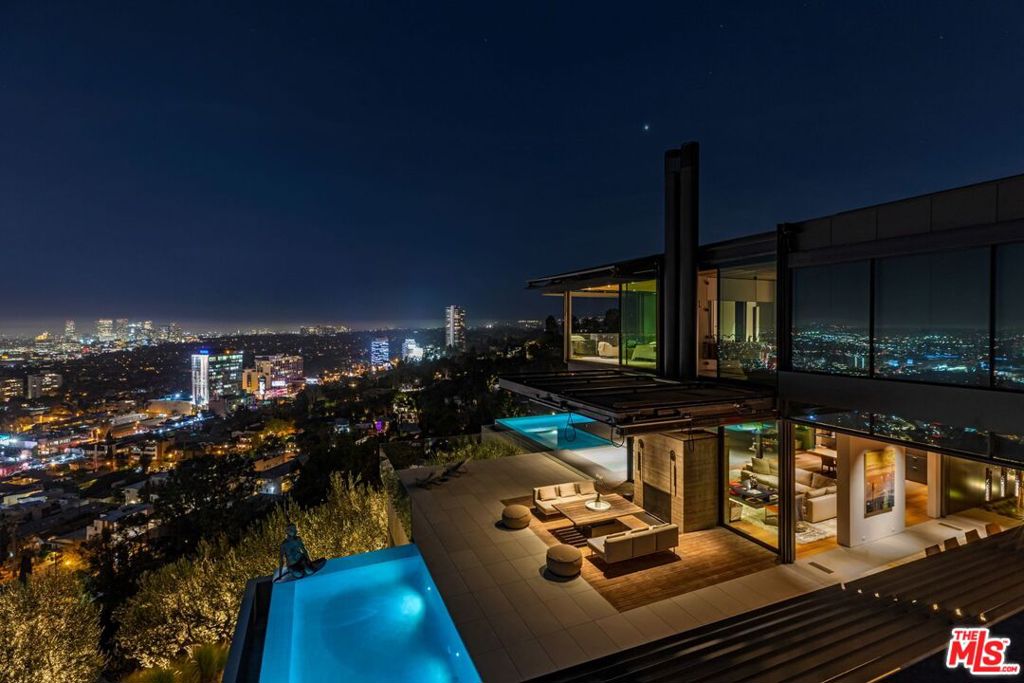 Designed by Olson Kundig one of the greatest modern architecture firms of our time. Set on a promontory blessed with explosive panoramic views taking flight over Los Angeles. This industrial organic modern inspires & touches all senses of the human spirit. A 6-year project that spared no expense; unbranded organic wood, stone & board formed concrete harmoniously combine to form a masterpiece. Enter a flawlessly executed sensory experience featuring hidden panels & design features that reveal at the touch of a button. A tri-level entertainer's compound fit for intimate & large gatherings of up to 250. 15-car auto gallery gives a nod to LA car culture. Dramatic guillotine doors open to expansive deck with fireplace, lounge & array of pools that spill out over the LA skyline. Transport to the South of France in a grove of 125 yr. old olive trees surrounding the property. Designed with the philosophy of uninterrupted modern elegance in mind, this is the Bond house of the future.