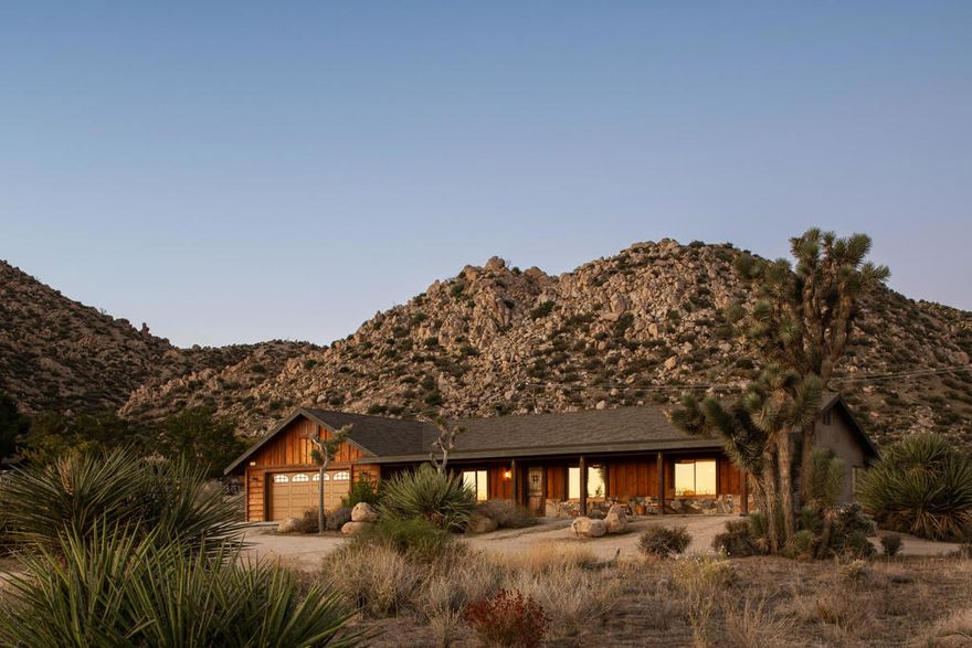 A private desert hideaway in Pioneertown set on just under 2.5 acres, offering wide open views, modern finishes, and a valuable second parcel for added space, privacy, or future potential.Designed with a refined blend of rustic and contemporary elements, the home features soaring wood ceilings, large windows that frame the surrounding mountains, and a spacious interior layout centered around a striking wood-burning fireplace. The kitchen includes elevated materials, custom wood cabinetry, and an easy flow into the dining and living areas, creating a comfortable setting for everyday living and gatherings.The home offers three generous bedrooms and three baths, including a well appointed primary suite with a walk in shower, dedicated vanity area, and a soaking tub oriented toward the desert landscape. A bright flex room adds a dedicated space for work, creativity, or quiet retreat, and the large garage provides ample storage or workshop potential.Outdoor areas include a wood deck, cowboy pool, spa, BBQ and dining area, and multiple lounge spaces for sunrise, sunset, and stargazing. The combined parcels create a rare sense of openness while still offering defined outdoor living spaces throughout the property.Located within walking distance to downtown Pioneertown, Red Dog, and Pappy and Harriet's, and a short drive to Joshua Tree National Park and the shops and restaurants of the High Desert.A standout desert property with modern construction, elevated materials, generous interior volume, and a valuable bonus parcel, ideal as a full time residence, private retreat, or an incredible opportunity to create a premium short term rental.