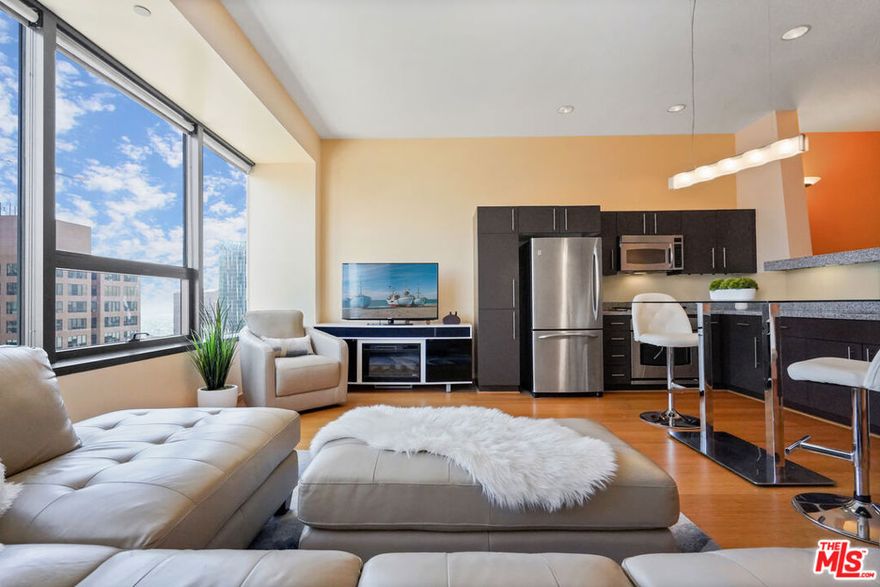This stunning contemporary residence showcases floor-to-ceiling windows framing breathtaking panoramic views of DTLA's skyline. The open-concept layout features a sleek modern kitchen with GE Profile stainless steel appliances, granite countertops, and European-style cabinetry. The elevated bedroom offers a sense of separation and privacy, complemented by a spacious walk-in closet. Additional highlights include rich wood flooring throughout, an in-unit washer and dryer, and a spa-inspired bath with a soaking tub. Enjoy resort-style amenities on the spectacular 17th-floor Sky Deck complete with a heated infinity pool, elevated spa, cabanas, lounge beds, BBQ grills, wet bar, and fire-pit lounge with sweeping skyline vistas. Residents also have access to a state-of-the-art fitness center, media and conference rooms, EV charging stations and a 24-hour attended lobby. Ideally located near world-class dining, entertainment, and shopping at LA Live, The Bloc, Fig at 7th, and Whole Foods. ***Furnished. Some utilities and 2 parking spaces are included.***