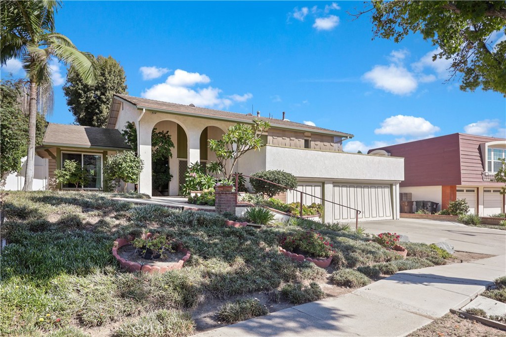 Opportunity to own a home in the Sunny Hills neighborhood of Fullerton! This 4 bedroom, 3 bathroom, 2,418 sq. ft, "tri-level" home offers space, comfort, and endless potential. Located in the desirable Fullerton Joint Union High School District, with access to Sunset Elementary, Parks Junior High, and Sunny Hills High School. Enter through a grand double-door entry framed by two arches. Inside, the dramatic living room boasts high ceilings and tall arched transom windows, filling the space with natural light. The remodeled kitchen is the heart of the home, showcasing granite countertops, white cabinetry, stainless-steel appliances, and a unique octagonal layout. Expansive wraparound windows offer backyard views and flood the space with light, while a breakfast bar and dining nook provide plenty of room for casual meals. The windows open to the yard, creating a seamless indoor-outdoor flow for gatherings. The family room offers a fireplace and a wall of built-in cabinetry with glass display cases, plus direct access to the backyard. On the first floor, a converted garage space creates a versatile bedroom, office, or guest room near a full bath. Upstairs, the master suite overlooks the backyard, while two bedrooms share access to a wraparound balcony. The master bath features mirrored closet doors and a recently remodeled shower/toilet room with new flooring, fixtures, and a stylish pebbled shower floor. The backyard is spacious with grassy and concrete areas, perfect for gardening, outdoor dining, or entertaining. This home is brimming with potential and offers a prime opportunity to personalize to your liking. With a little TLC, this Sunny Hills gem can easily become your dream home.