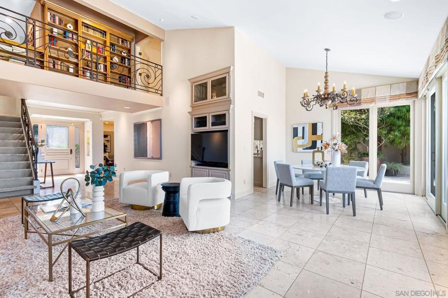 Sweeping easterly views and effortless elegance are yours from this refined residence tucked within Windemere’s exclusive guard-gated community. Vaulted ceilings, abundant natural light, and a neutral palette create an ambiance of comfortable sophistication throughout the 3-bedroom, 3-bathroom layout. Flowing living areas are ideal for entertaining and everyday enjoyment, with a well-equipped chef’s kitchen featuring quartz-topped counters, a center island, stainless appliances, and a built-in breakfast nook. The entry-level primary suite offers a large walk-in closet plus two additional closets, and a luxe stone bath with dual vanities, skylights, and a spacious shower with a floral accent wall. Upstairs, a generous bedroom and bath are connected by a catwalk overlooking the living room—lined with bookshelves, creating a cozy loft-style library. Four sets of sliding doors open to a wraparound garden patio with mature landscaping, a built-in barbecue, and a soothing fountain—an inviting setting to embrace the city lights and mountain vistas. The third bedroom is currently used as an office without a finished closet. Thoughtfully designed storage in nearly every space contributes to pristine, organized living. Residents of Windemere benefit from 24/7 guard-gated access and resort-inspired amenities including two pools, a spa, fitness center, lighted tennis & pickleball courts, clubhouse, RV/boat parking, and scenic park-like grounds with walking paths. Perfectly located in the hills of La Jolla, just minutes from The Village, beaches, and a wide array of shopping & dining.